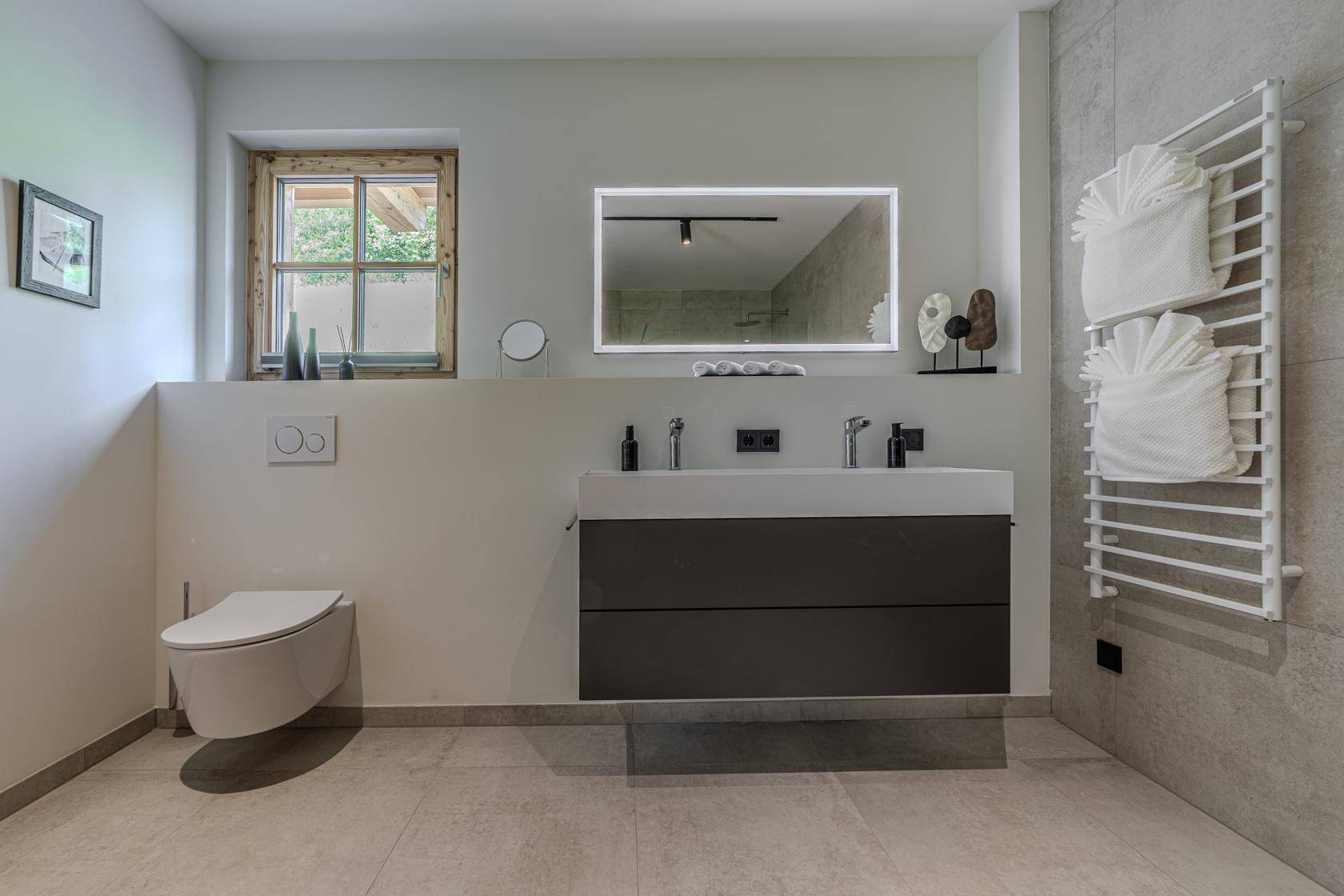Elegantes Badezimmer mit schwebendem Waschtisch, Wand-WC und beheiztem Handtuchhalter.