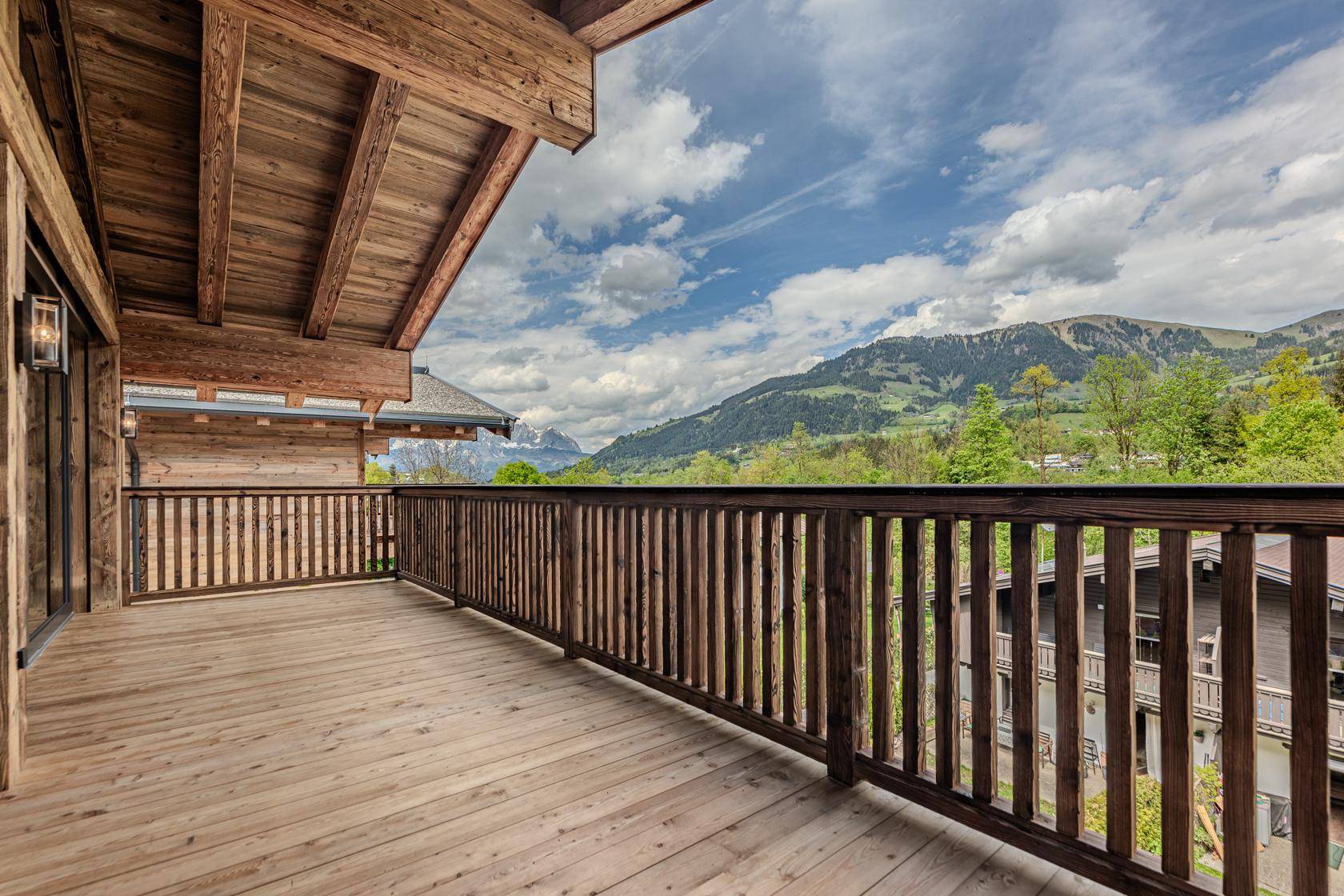 Geräumiger Holzbalkon mit atemberaubendem Blick auf die umliegende Bergwelt.