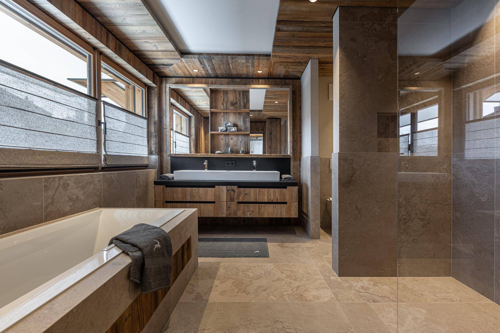 Geräumiges Badezimmer mit begehbarer Dusche, Badewanne und Holzdetails.
