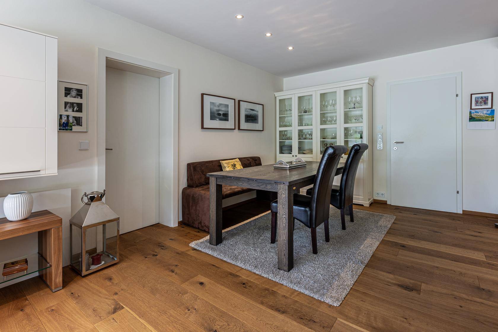 Heller Essbereich mit Holztisch, bequemer Sitzbank und Vitrinenschrank.