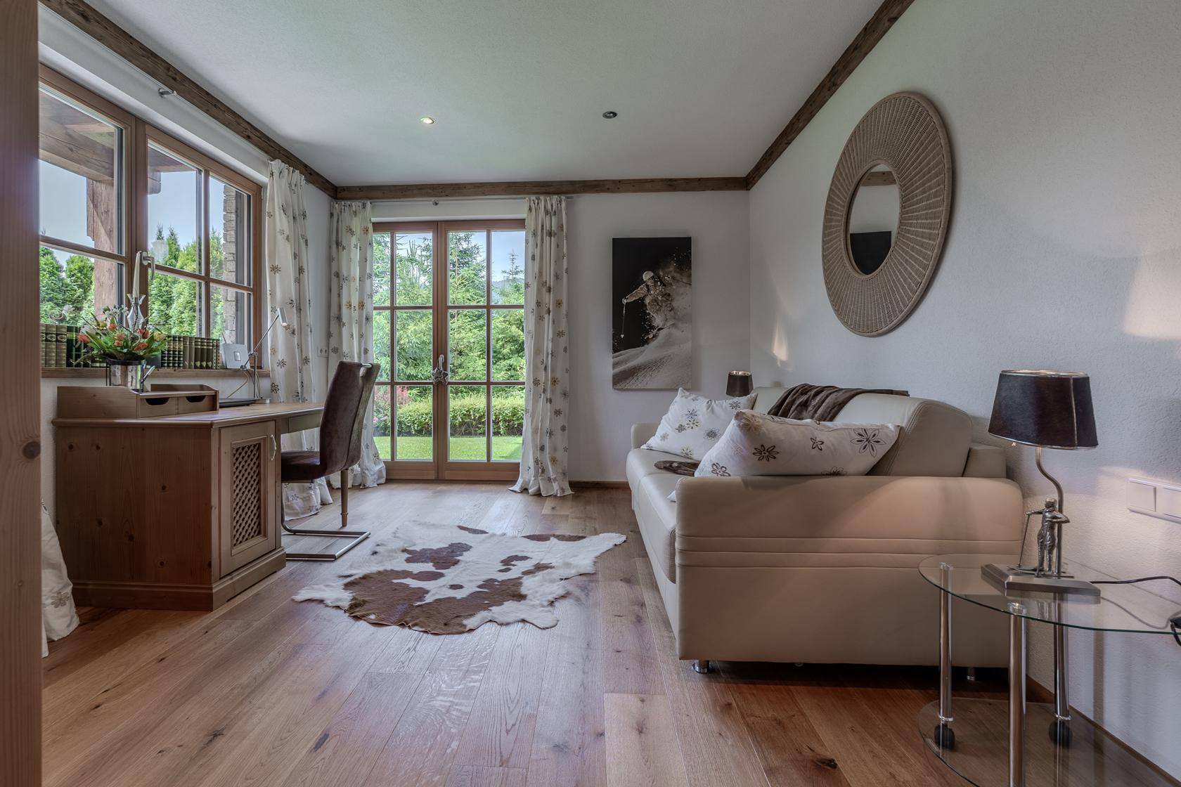Helles Arbeitszimmer mit Holzboden, Schreibtisch und Zugang zum Garten.