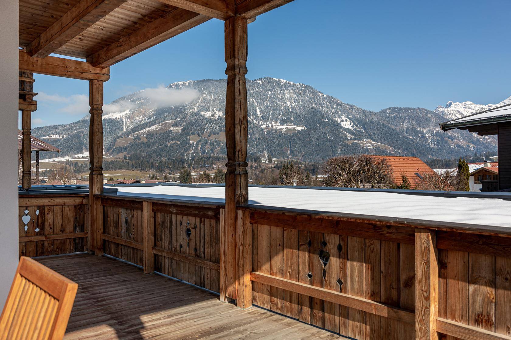 Geräumiger Holzbalkon mit atemberaubendem Panoramablick auf die verschneiten Alpen.