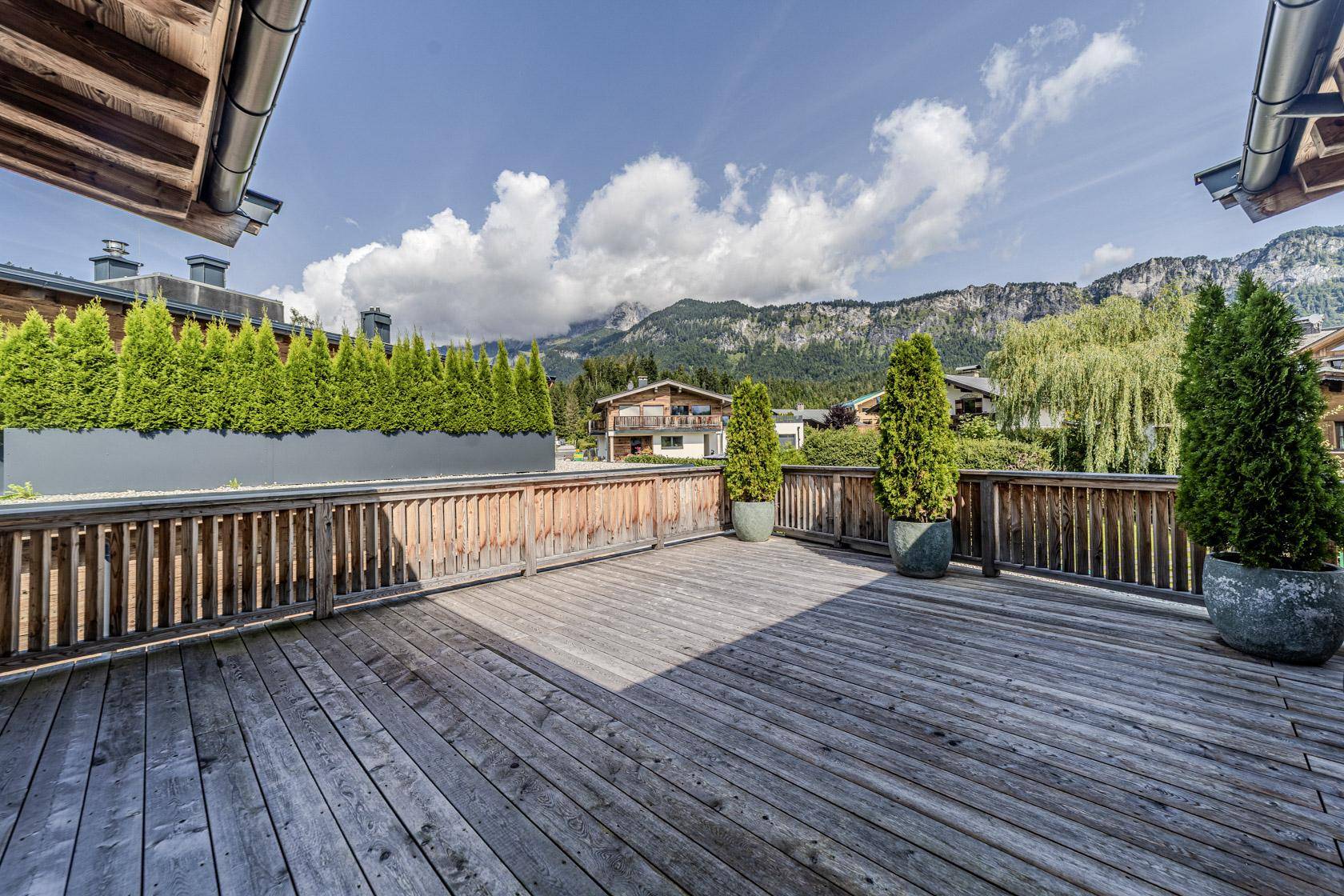 Geräumige Holzterrasse mit Bergblick und grünen Pflanzen, ideal zum Entspannen im Freien.