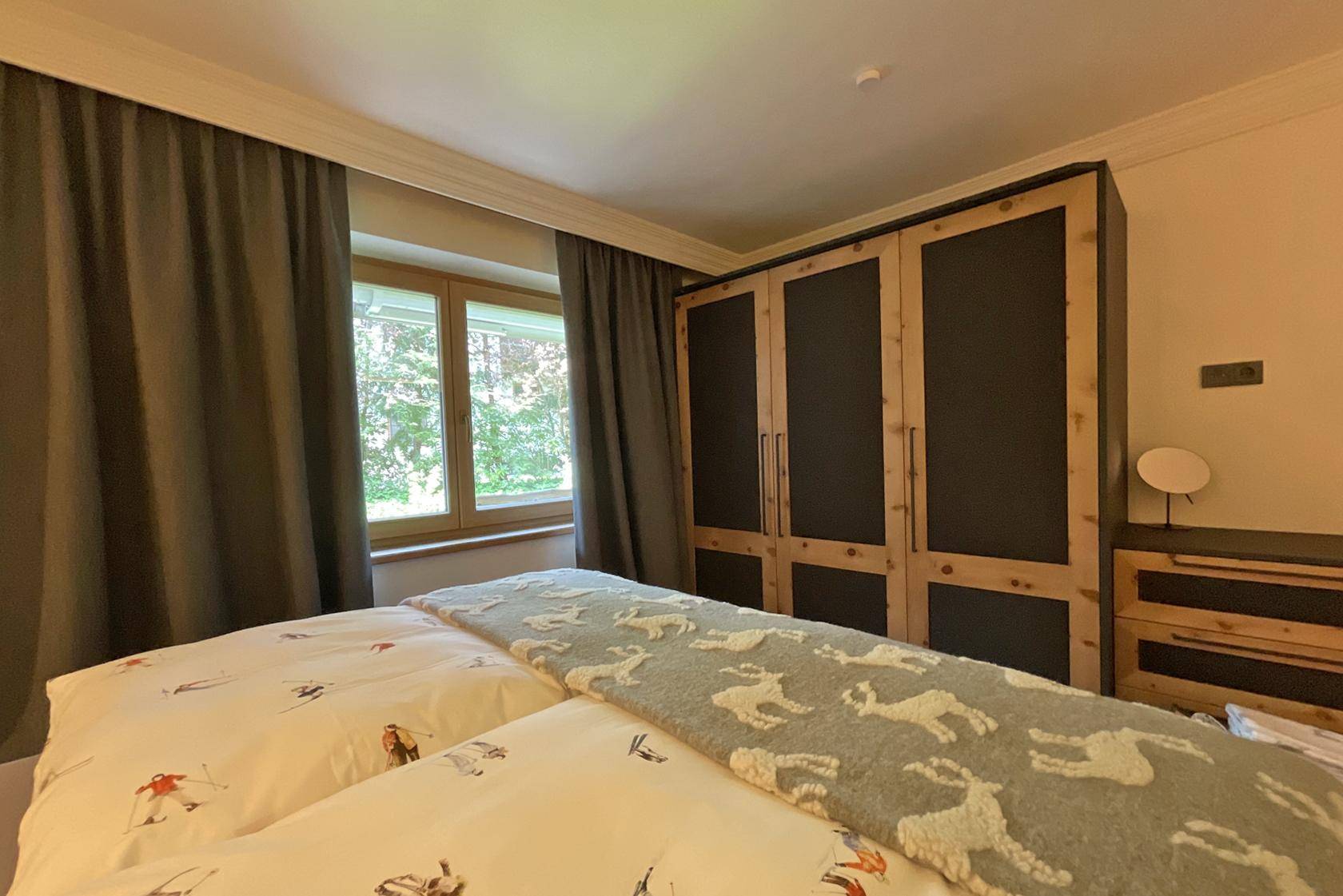 Schlafzimmer mit Doppelbett, Einbauschränken und Fenster mit Blick ins Grüne.