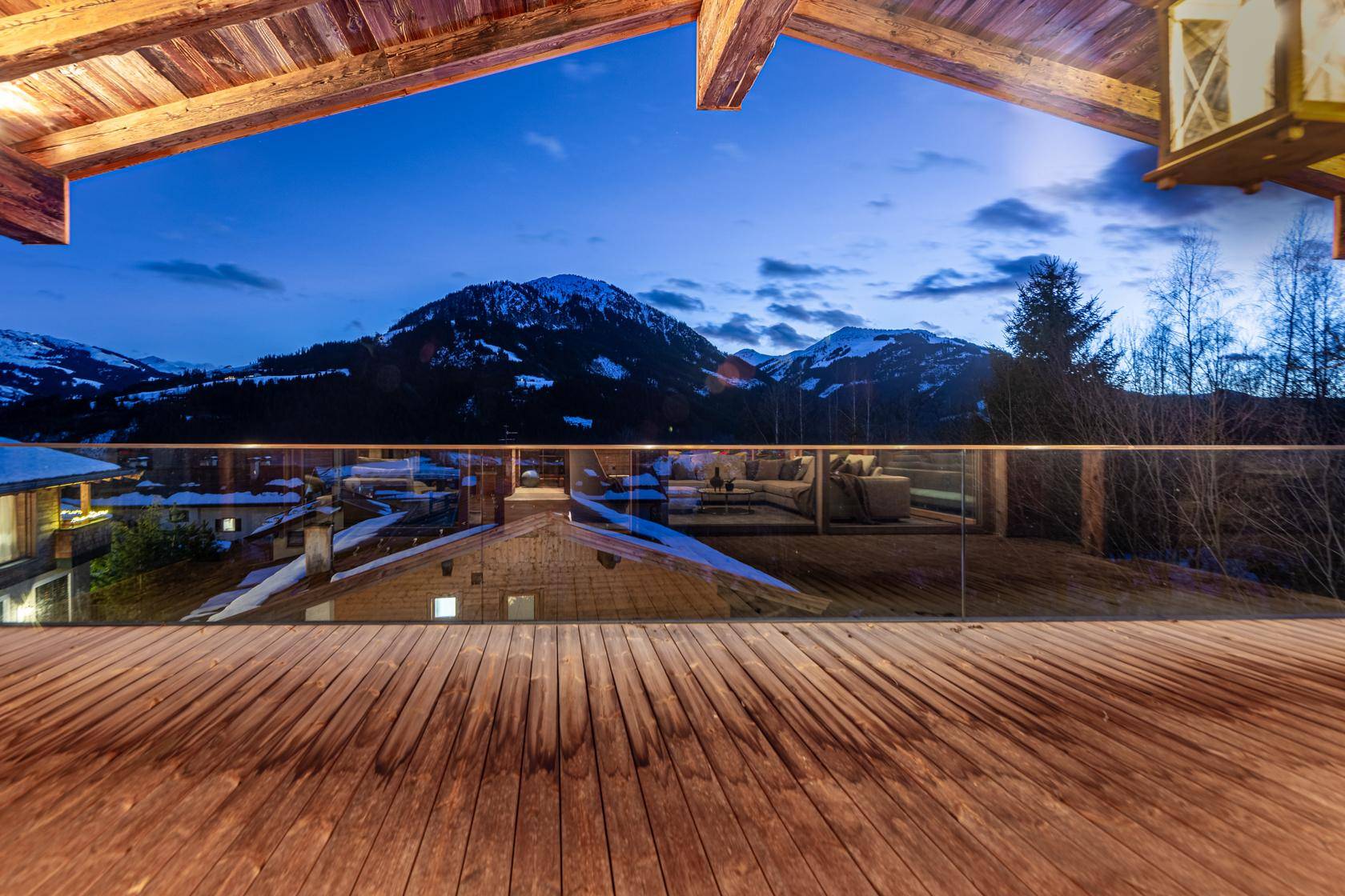 Große Holzterrasse mit Glasgeländer und atemberaubendem Blick auf die verschneiten Berge.