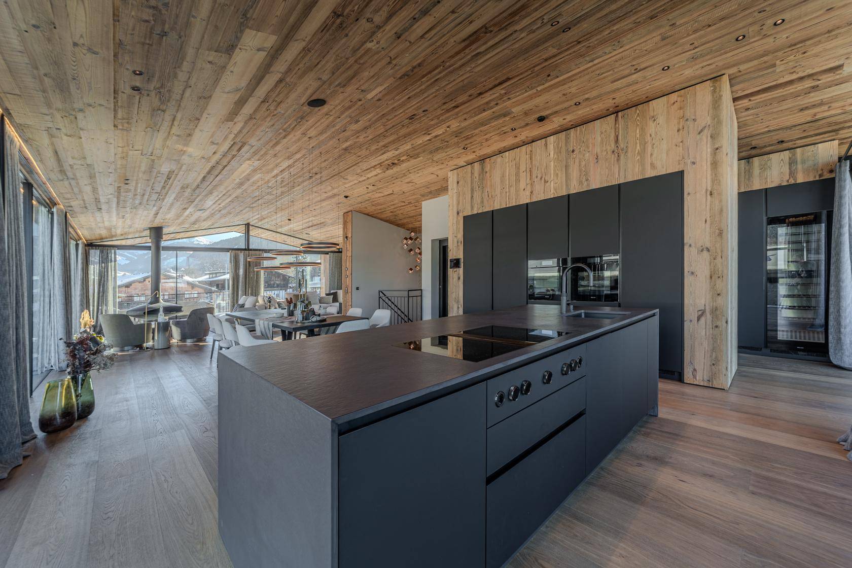 Moderne offene Küche mit dunkler Kücheninsel, integrierten Geräten und Holzboden.