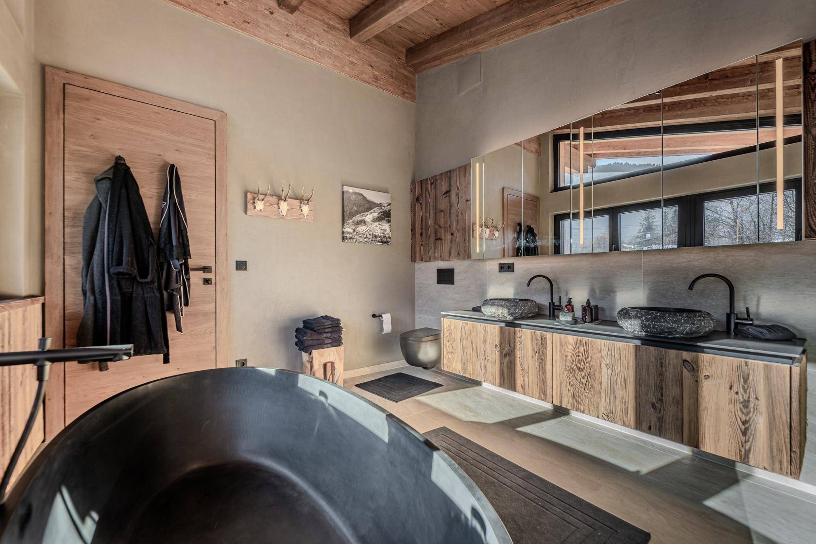Geräumiges Badezimmer mit Doppelwaschbecken, freistehender Badewanne und Holzelementen.