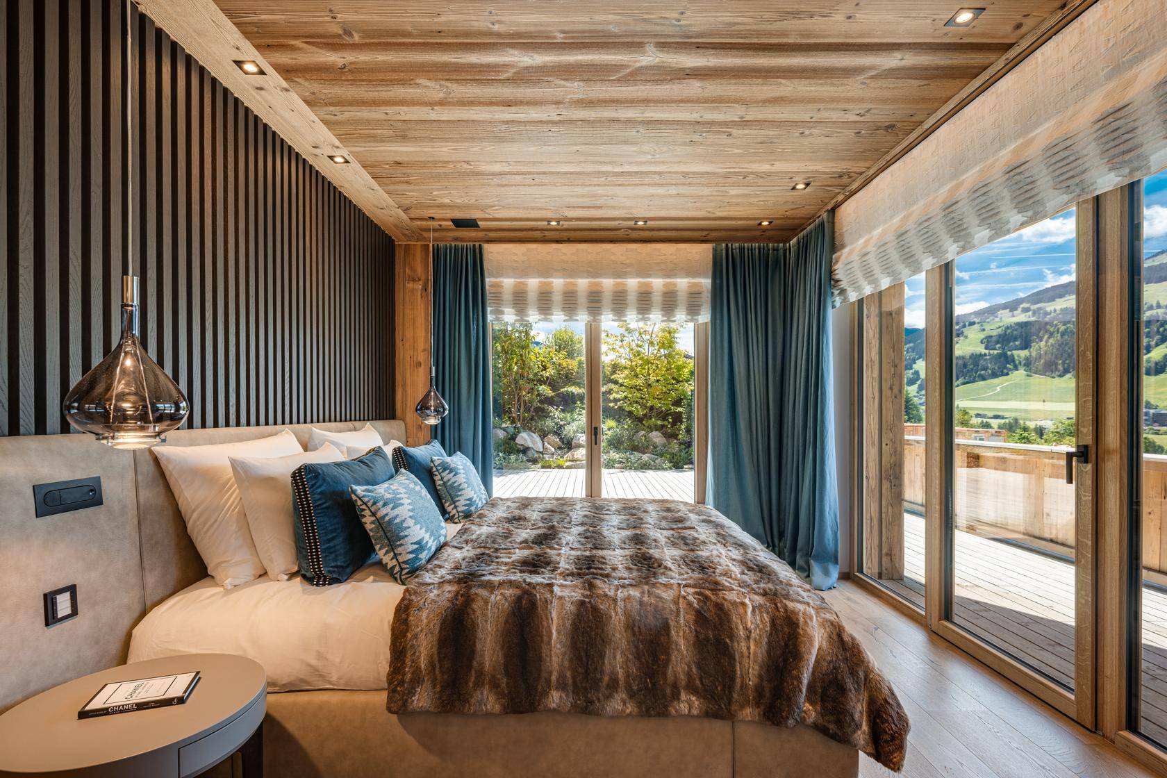 Helles Schlafzimmer mit Holzwänden, bequemen Bett und direktem Zugang zur sonnigen Terrasse.