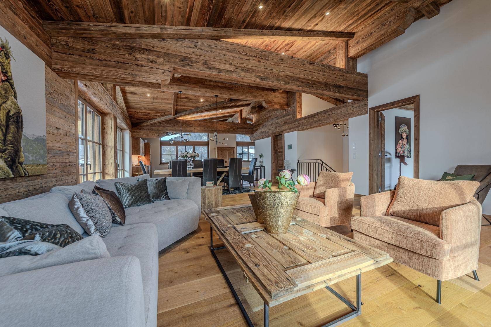 Heller Wohnbereich mit bequemen Sofas, Holzbalkendecke und rustikalem Couchtisch.