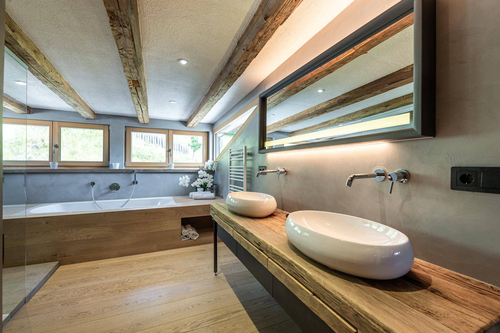 Elegantes Badezimmer mit Doppelwaschbecken, Badewanne und Holzbalken.
