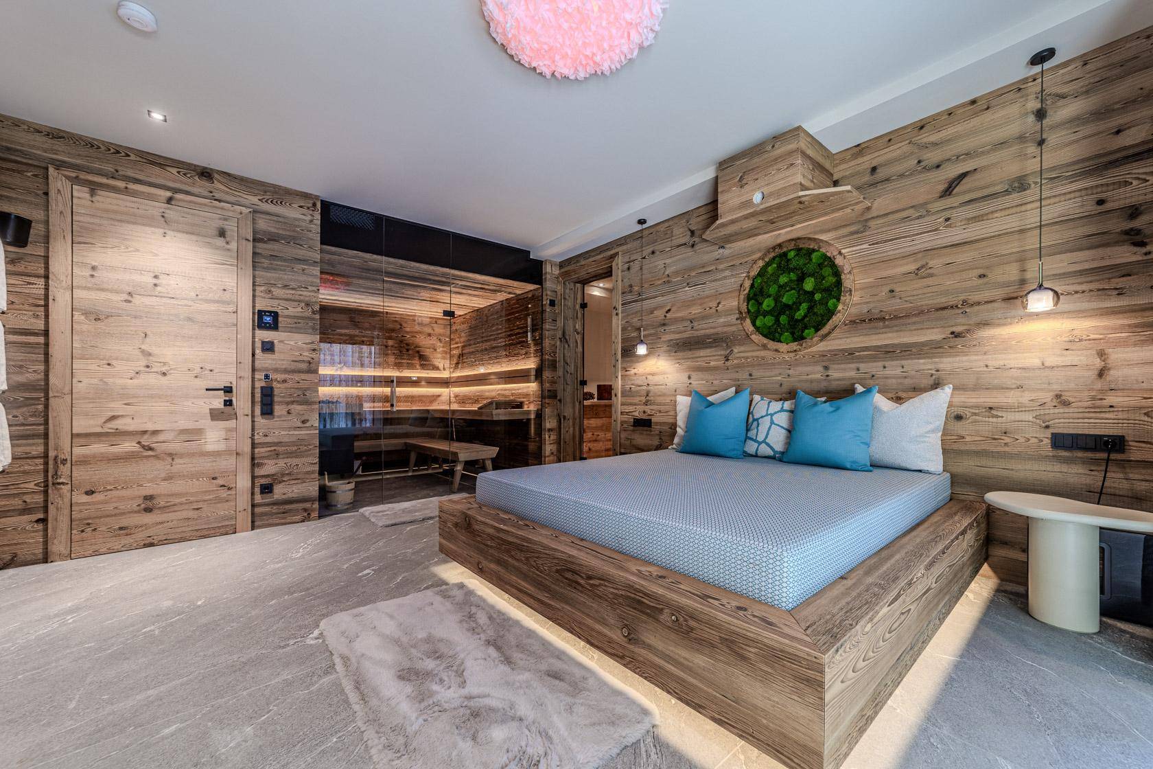 Schlafzimmer im alpinen Stil mit Holzwänden, modernem Bett und integrierter Sauna.