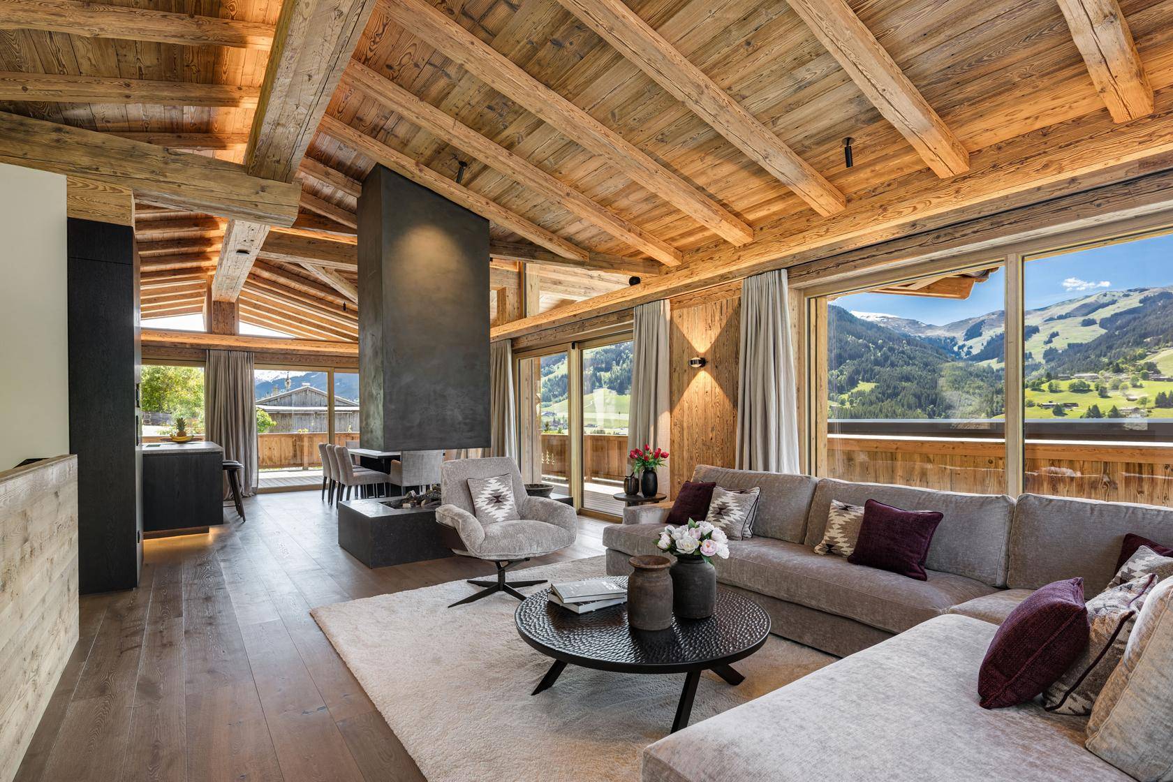 Großzügiger Wohnbereich mit gemütlicher Sitzecke, modernem Kamin und beeindruckendem Bergblick.