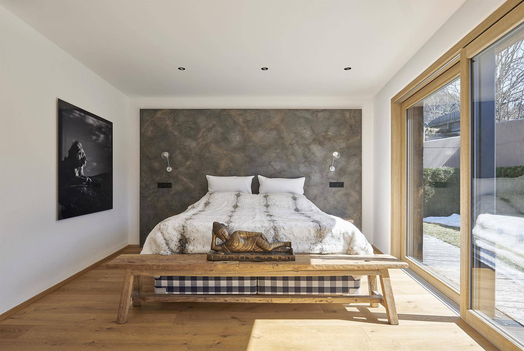 Helles Schlafzimmer mit Holzboden, großer Fensterfront und direktem Zugang zum Garten.