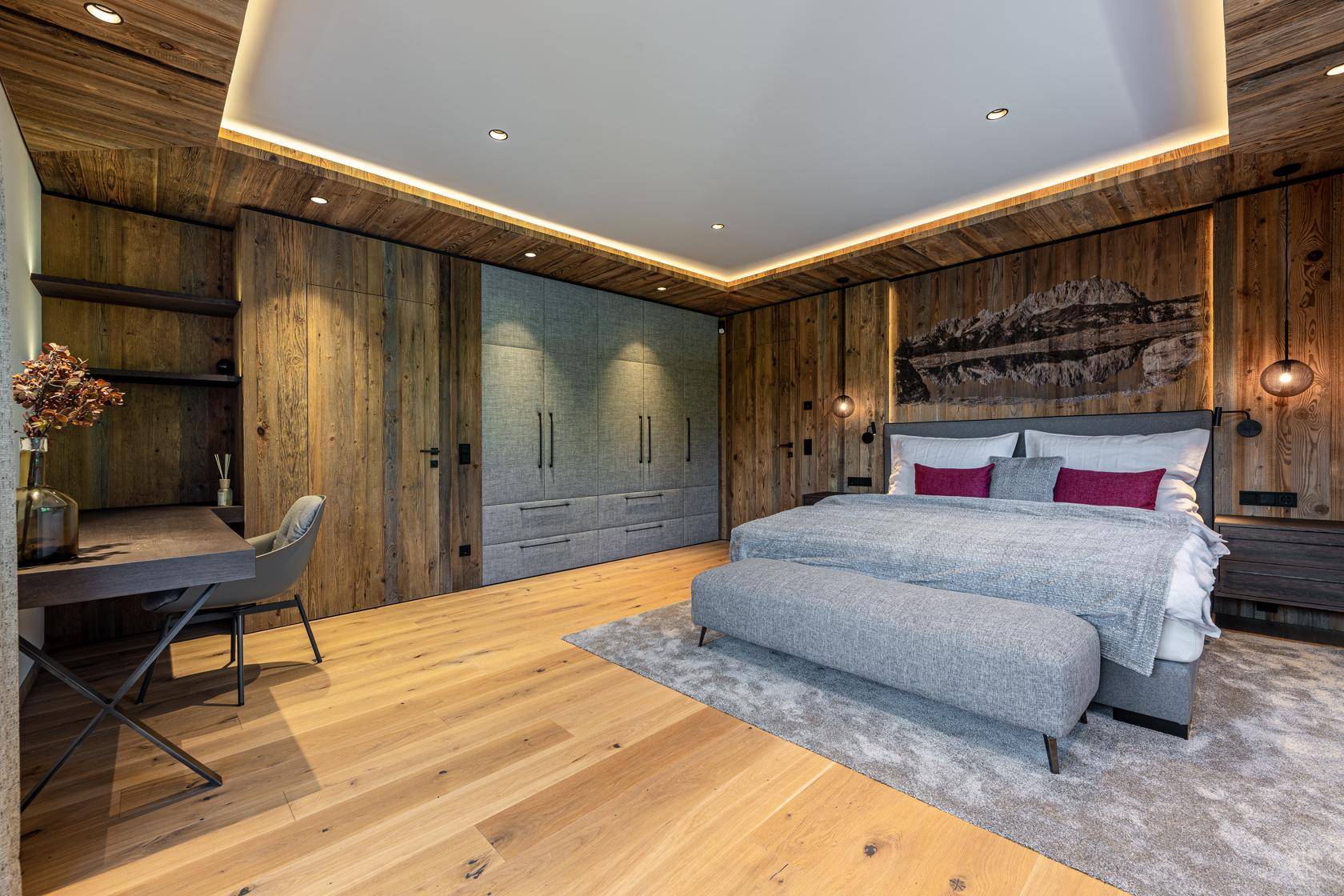 Gemütliches Schlafzimmer mit Holzwänden, Einbauschränken und indirekter Beleuchtung.