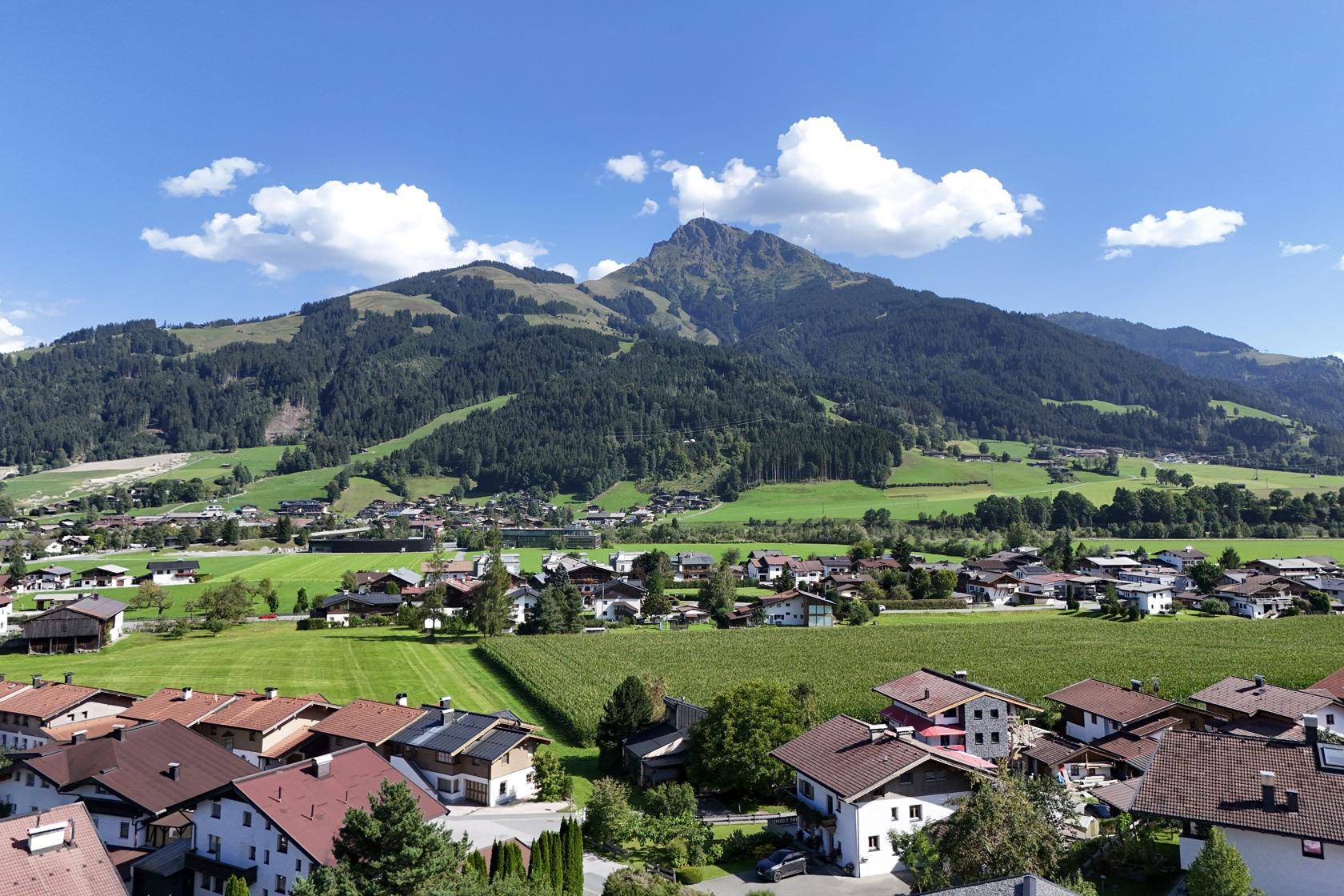Panoramablick auf ein malerisches Dorf in einem grünen Tal mit majestätischen Bergen.