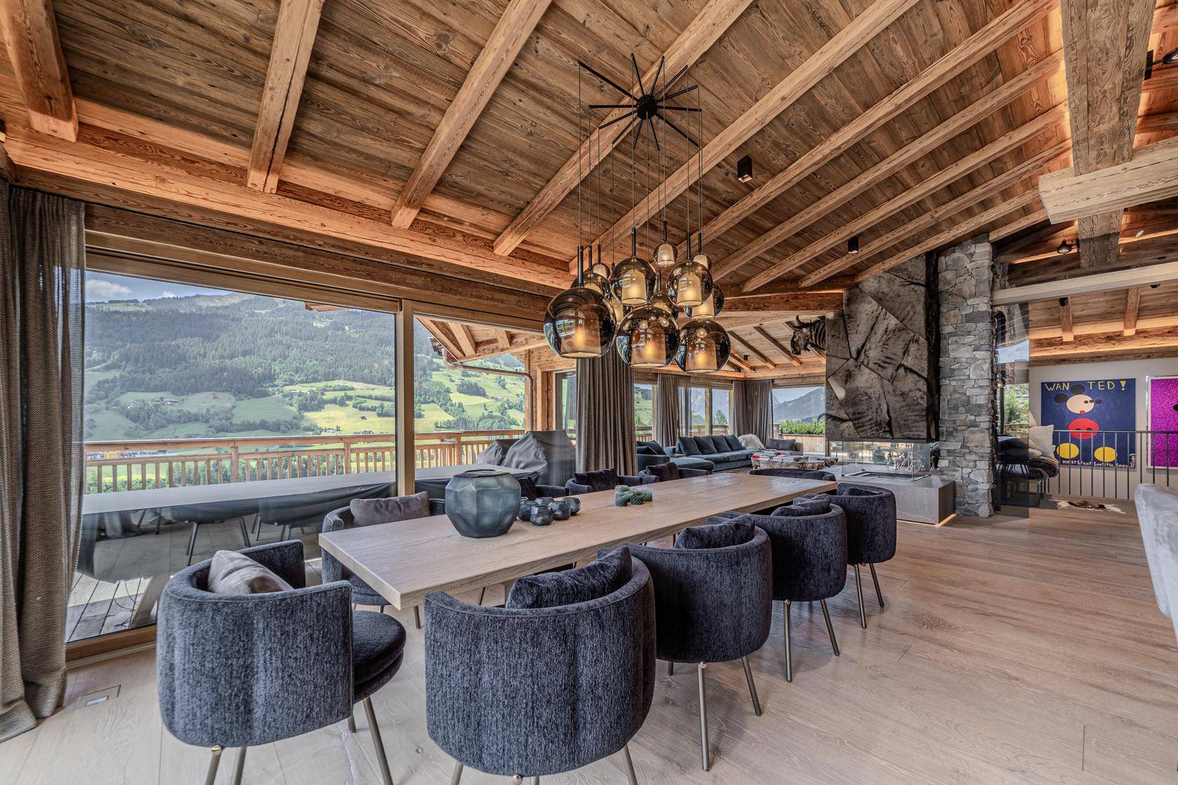 Offener Wohn- und Essbereich mit Holzbalkendecke, großem Esstisch und weitem Bergblick.