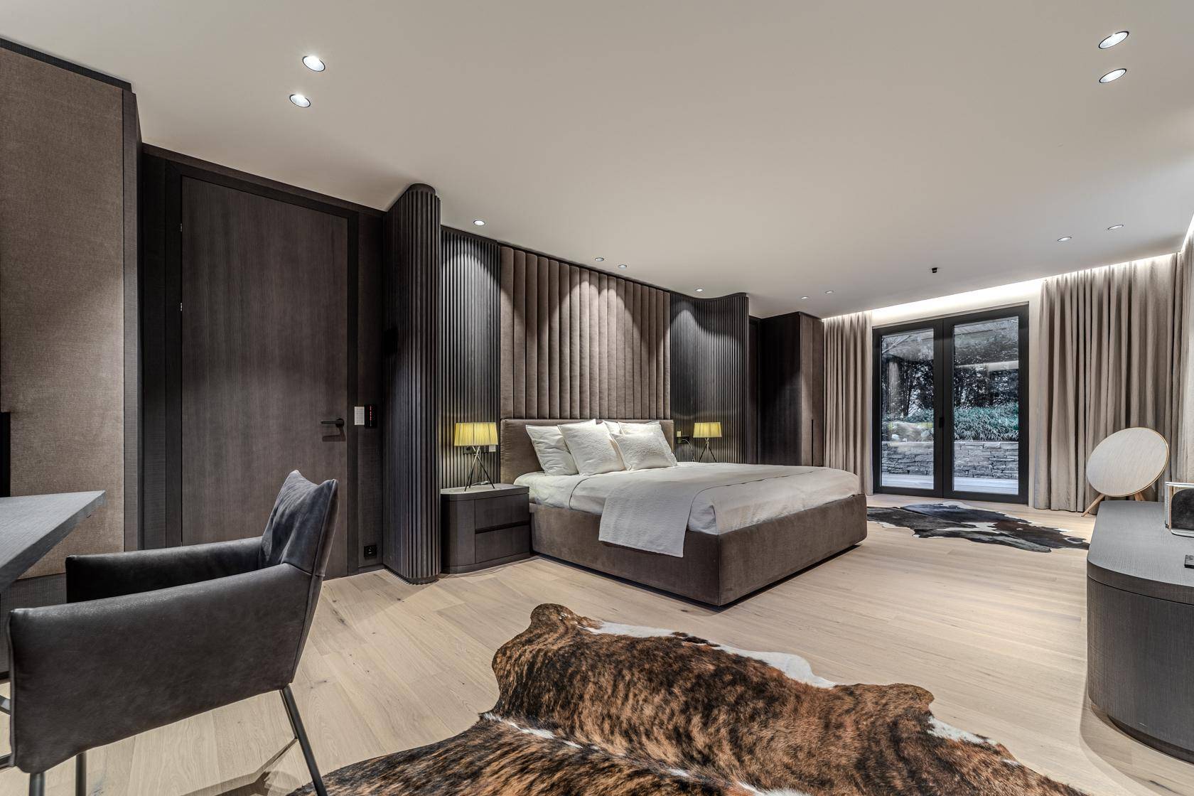 Modernes Schlafzimmer mit dunklen Holzakzenten, gepolstertem Kopfteil und Zugang zum Außenbereich.