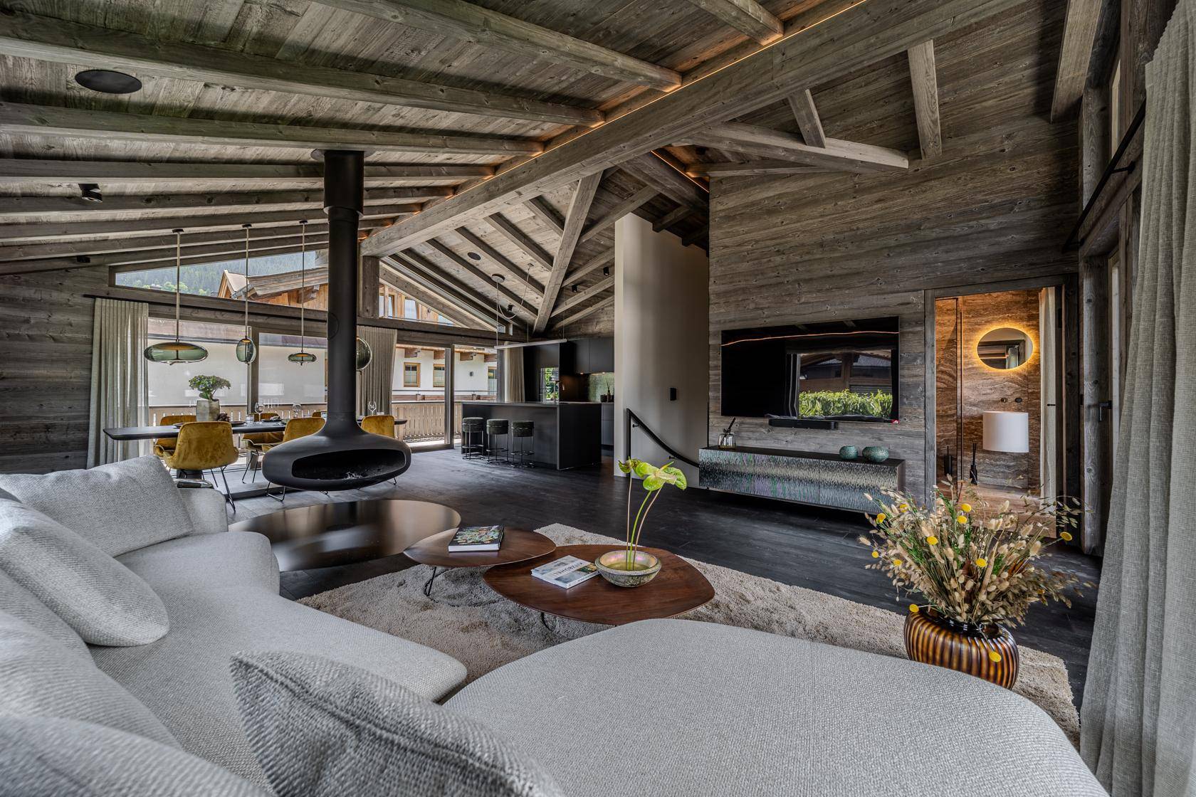 Heller Wohnbereich mit großem Sofa, Fernseher an der Holzwand und Blick auf den Essbereich.