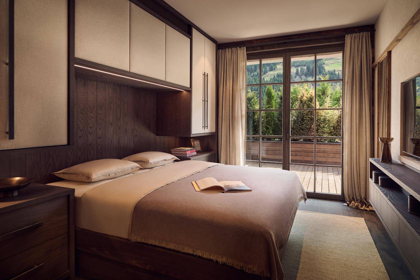 Komfortables Schlafzimmer mit Holzboden, Einbauschränken und Zugang zu einem Balkon mit Bergblick.
