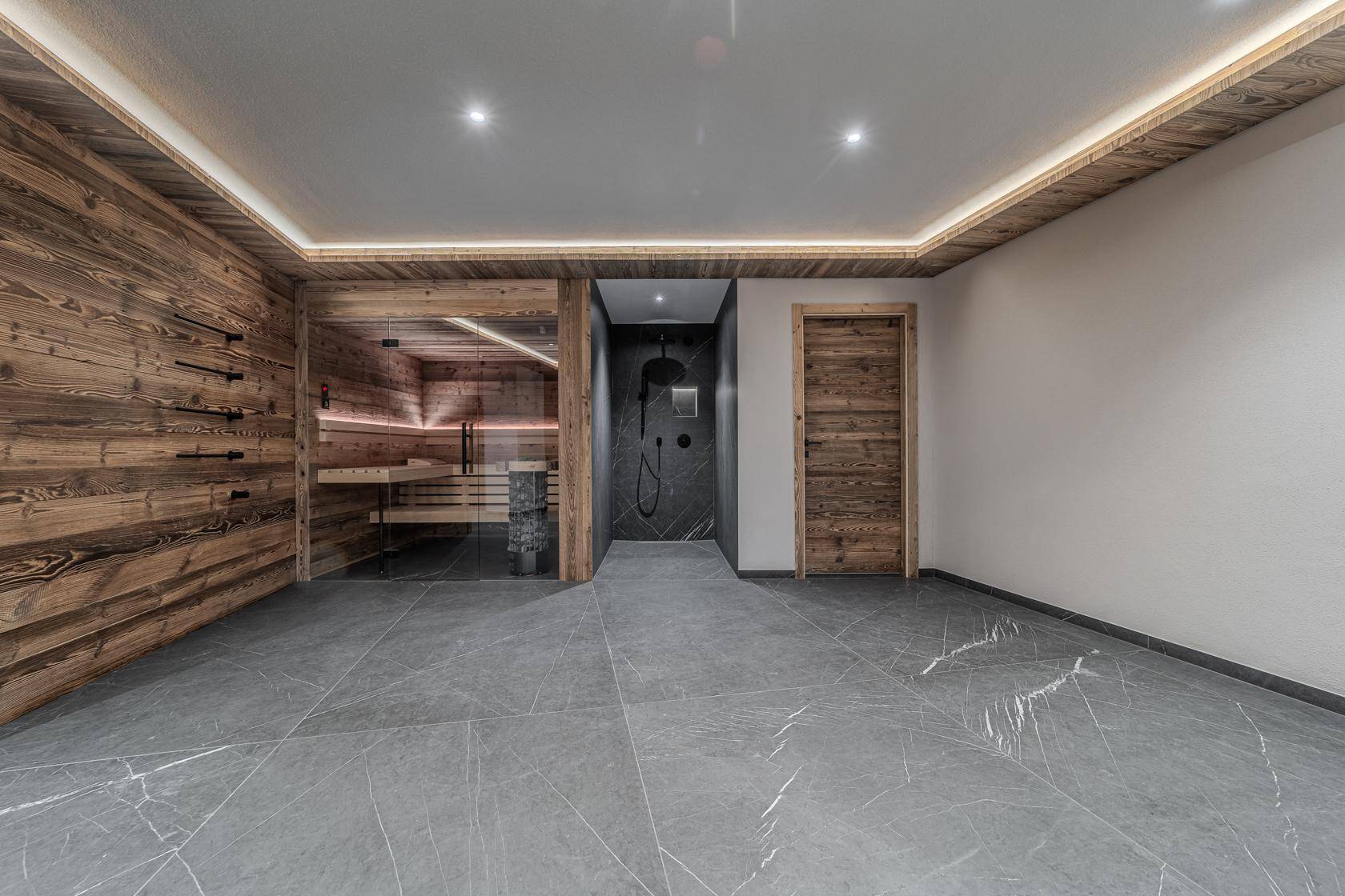 Moderner Wellnessbereich mit Sauna, separater Dusche und großformatigen Fliesen, perfekt zur Entspannung.
