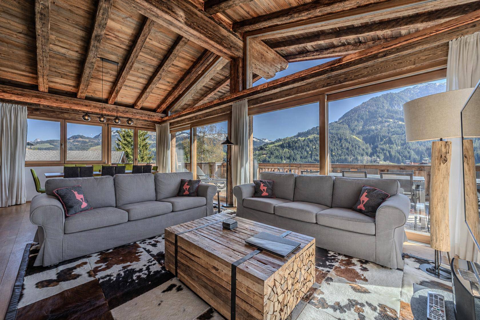 Heller Wohn-Essbereich mit Holzbalkendecke, bequemen Sofas und Bergblick.