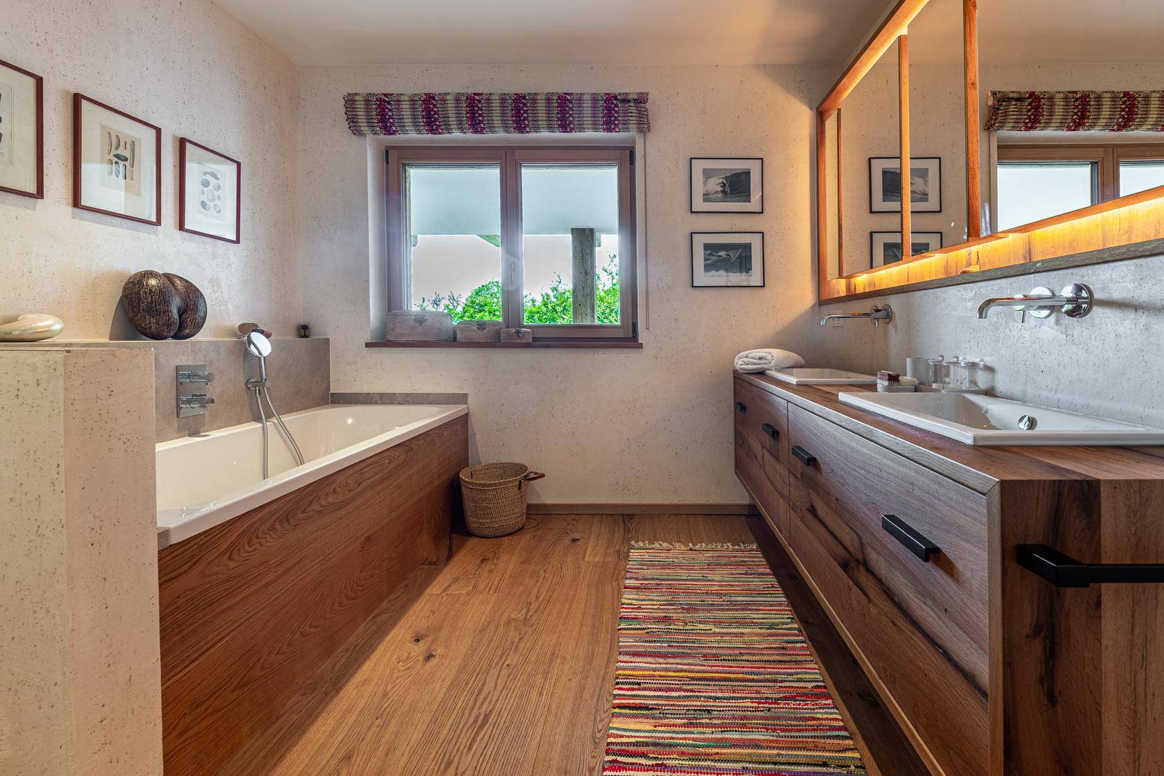 Modernes Badezimmer mit Holzwaschtisch, Doppelwaschbecken, Badewanne und Fenster.