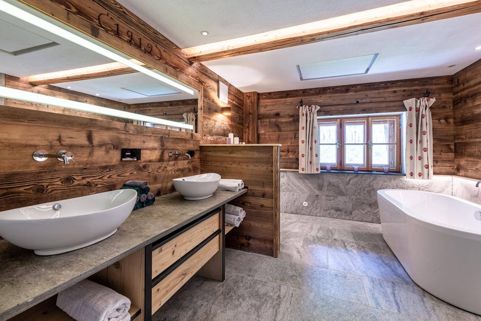 Luxuriöses Badezimmer mit Holzverkleidung, Doppelwaschbecken und freistehender Badewanne.