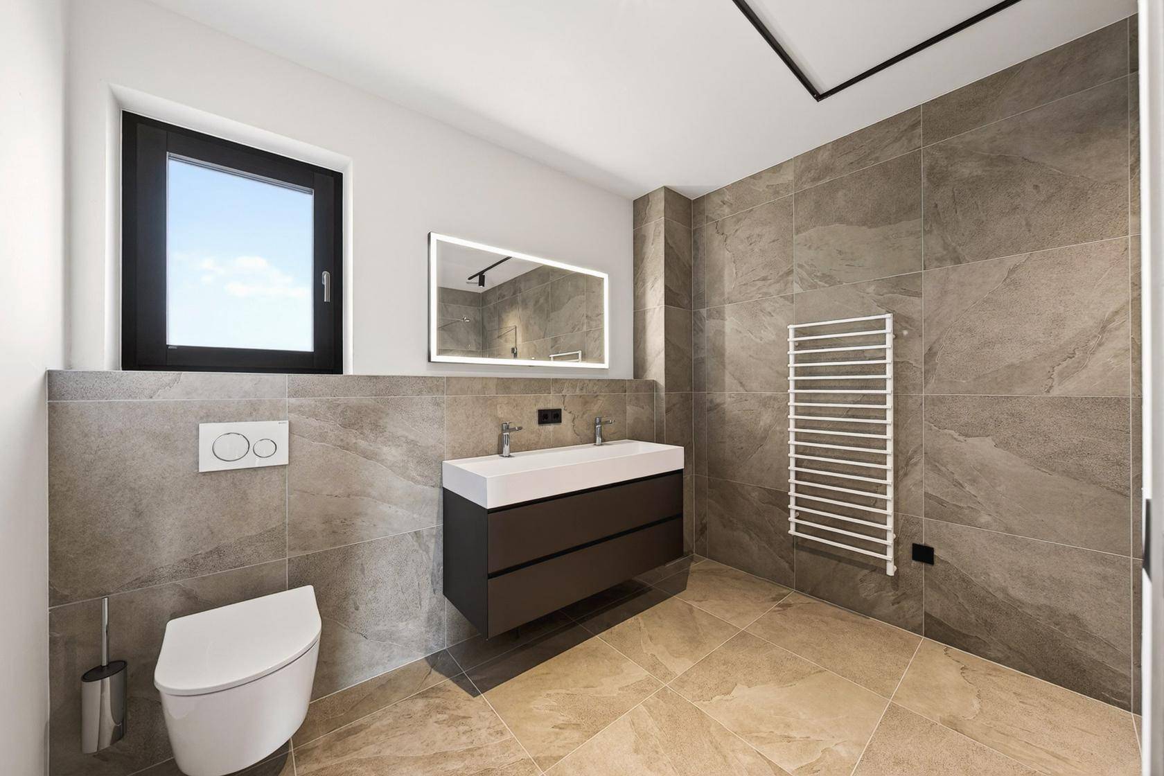 Elegantes Badezimmer mit modernen Fliesen, wandhängendem WC und Fenster für Tageslicht.