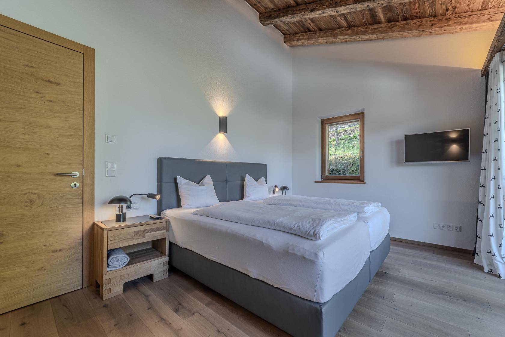 Helles Schlafzimmer mit Holzboden, bequemen Betten und Blick auf die Natur.