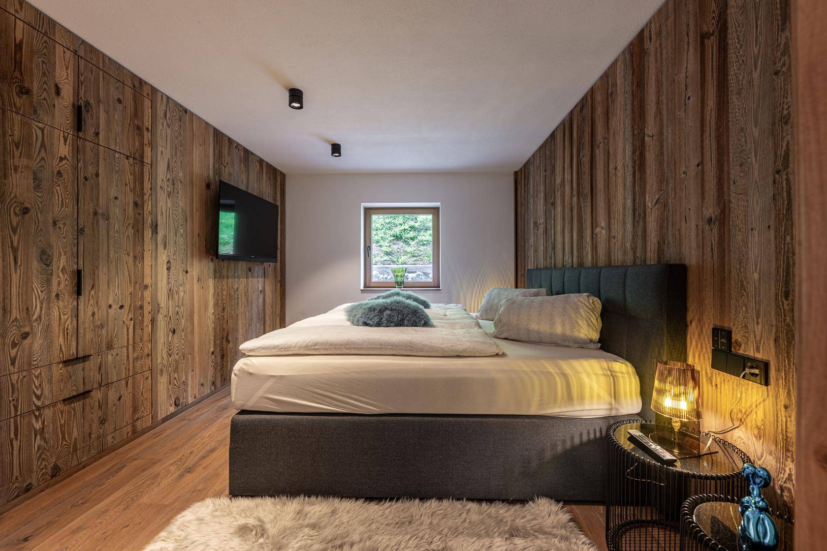 Schlafzimmer mit Holzwänden, Doppelbett und integrierten Holzschränken.