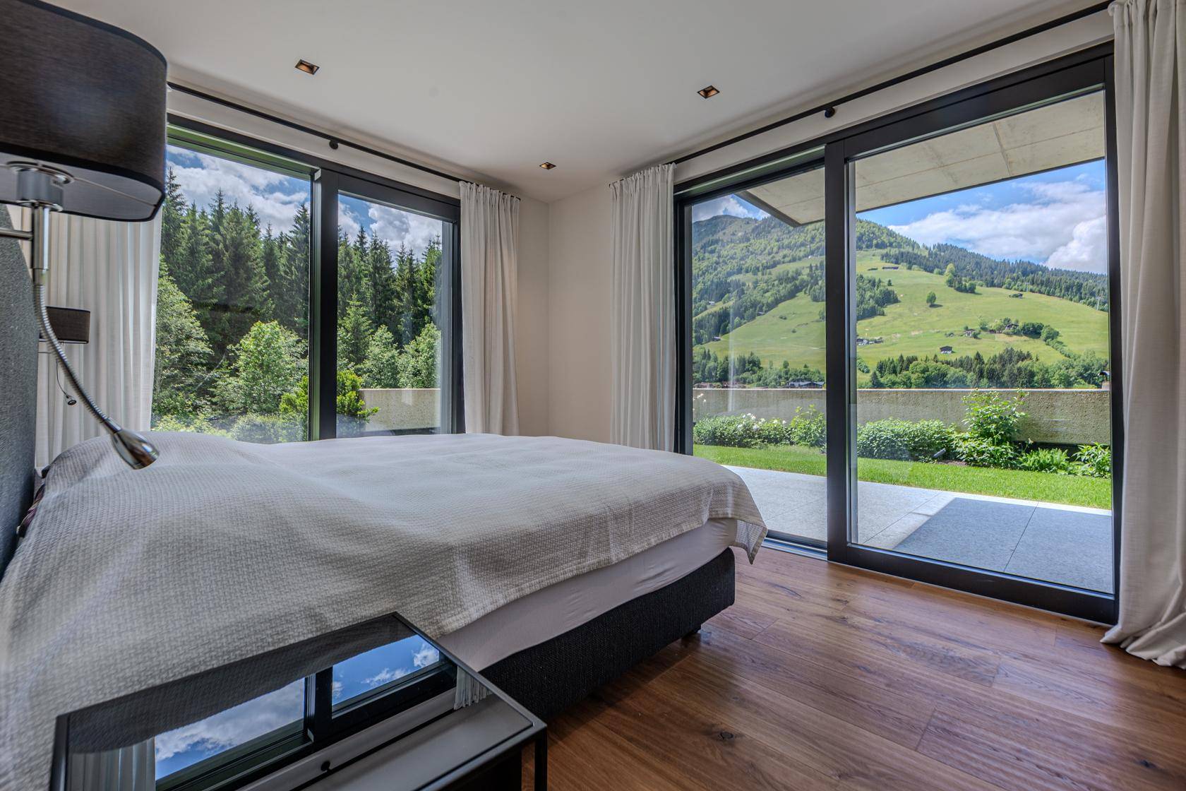 Helles Schlafzimmer mit Holzboden, großen Schiebetüren und direktem Zugang zum Garten.
