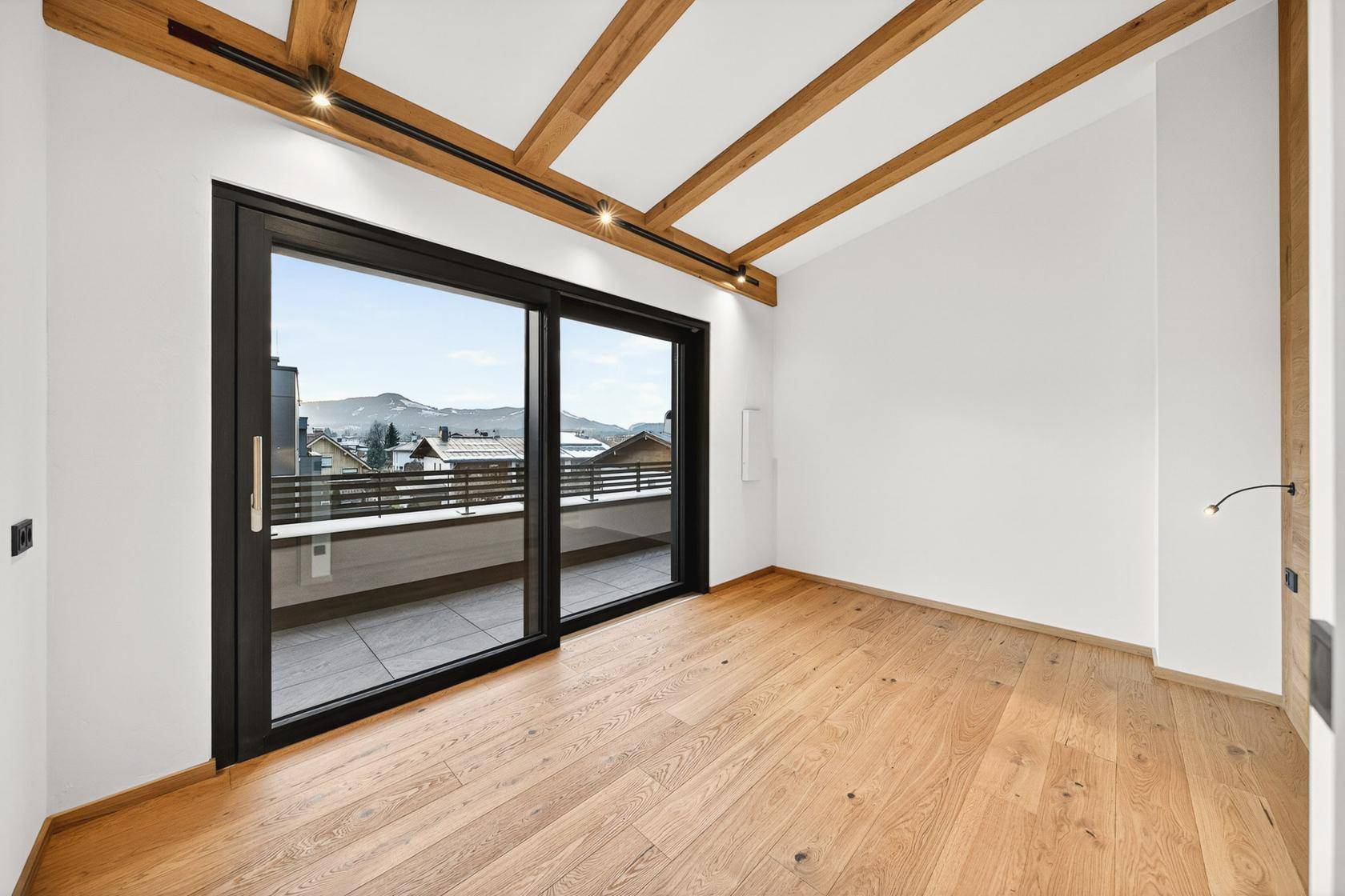 Helles Schlafzimmer mit Holzbalkendecke und Zugang zu einer privaten Terrasse mit Bergblick.
