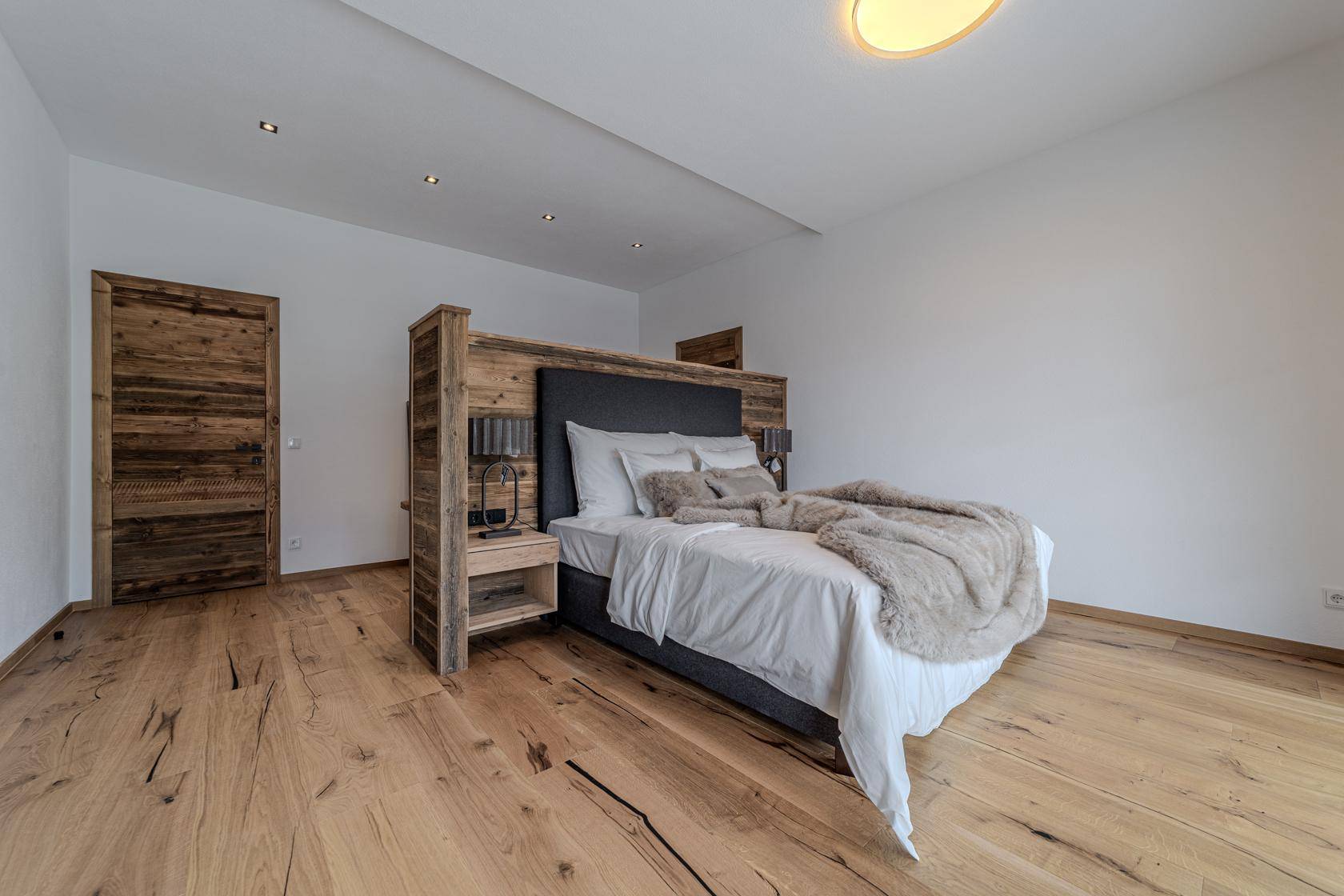 Modernes Schlafzimmer mit Holzboden, großem Bett und minimalistischer Einrichtung.