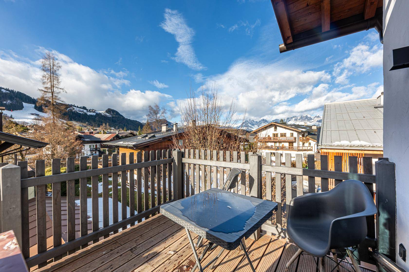Geräumiger Balkon mit Holzboden und Sitzgelegenheiten, ideal für entspannte Stunden mit Bergblick.
