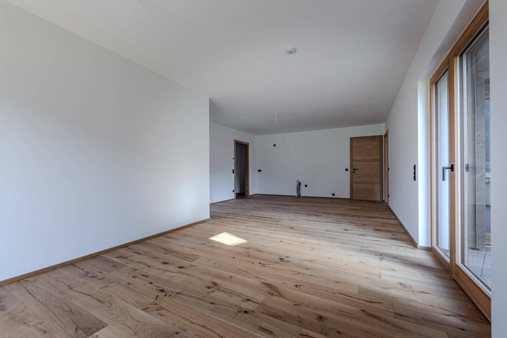 Geräumiges, unmöbliertes Zimmer mit Holzboden und weißen Wänden, bereit für individuelle Gestaltung.