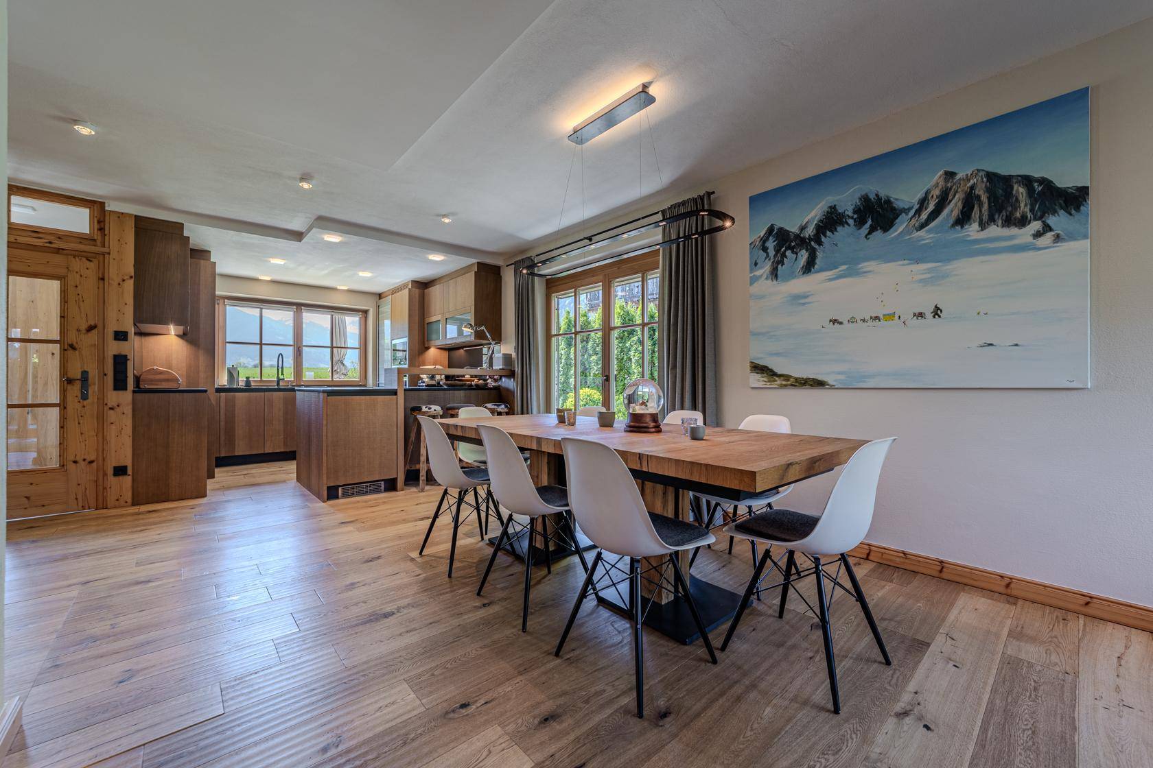 Geräumiger Essbereich mit Holztisch, modernen Stühlen und Blick ins Grüne.