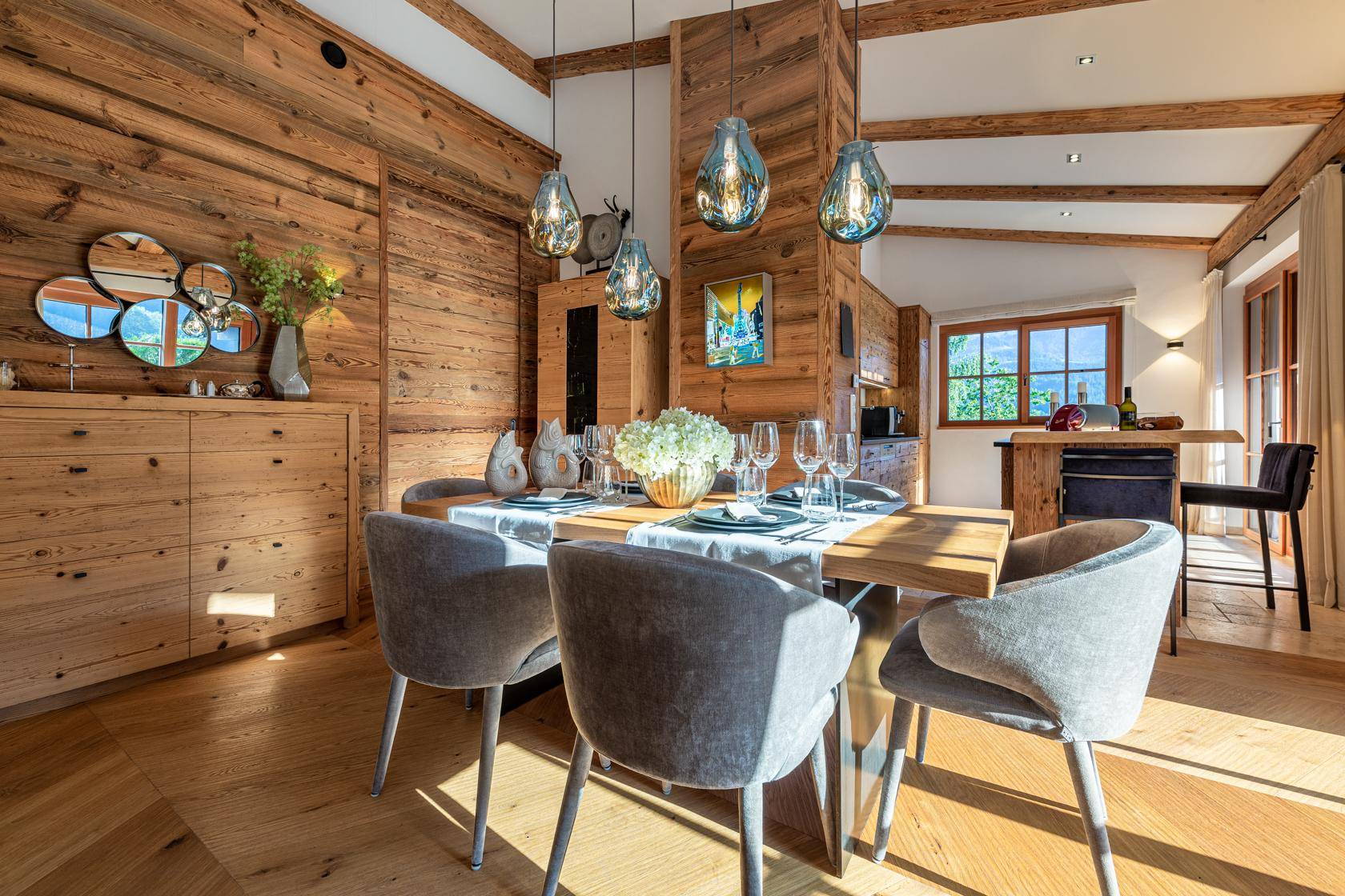 Stilvoller Essbereich mit Holzwänden, modernen Hängelampen und Zugang zur Küche.