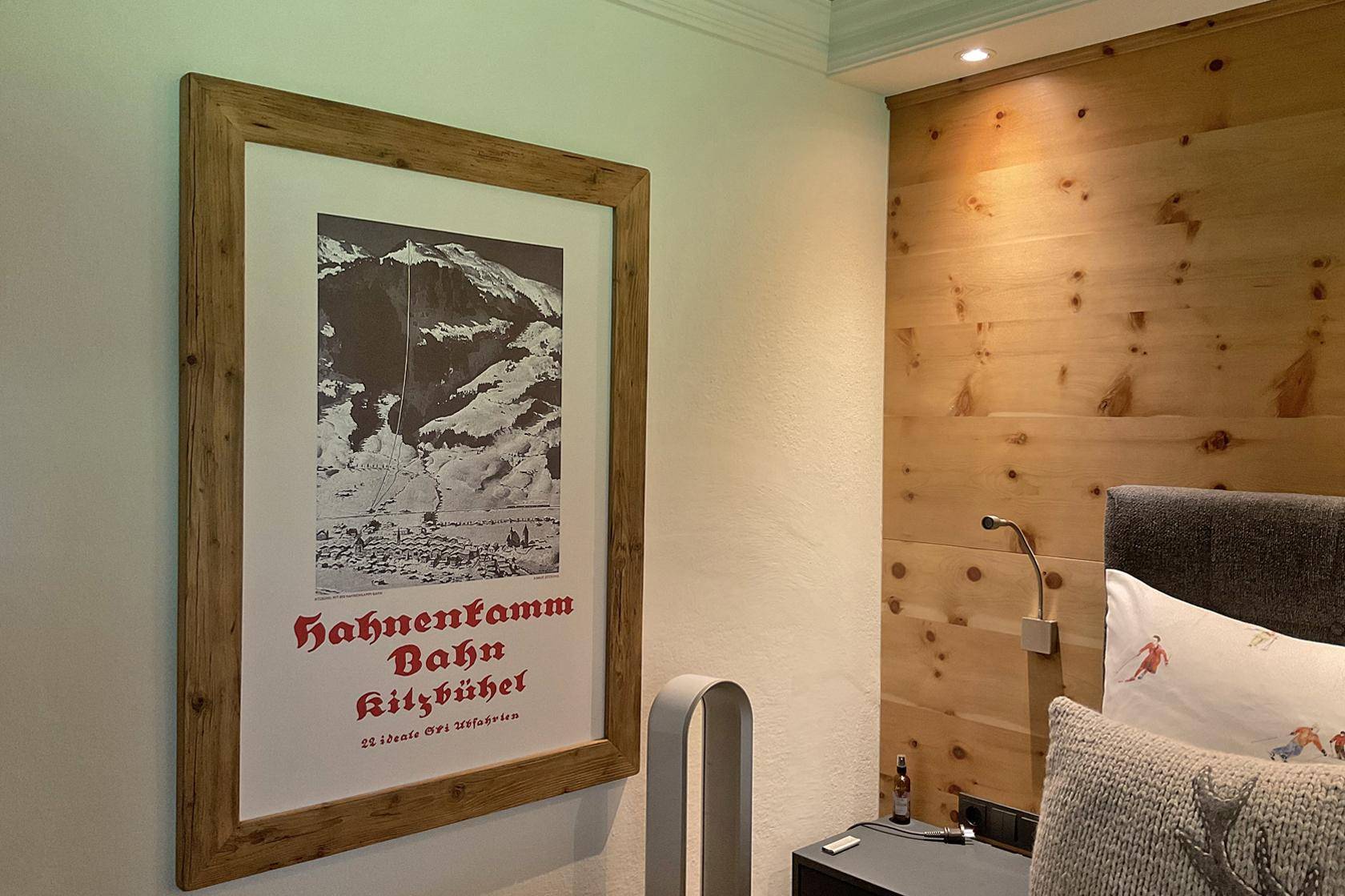 Schlafzimmer mit Holzwand, modernem Kunstwerk und indirekter Beleuchtung.