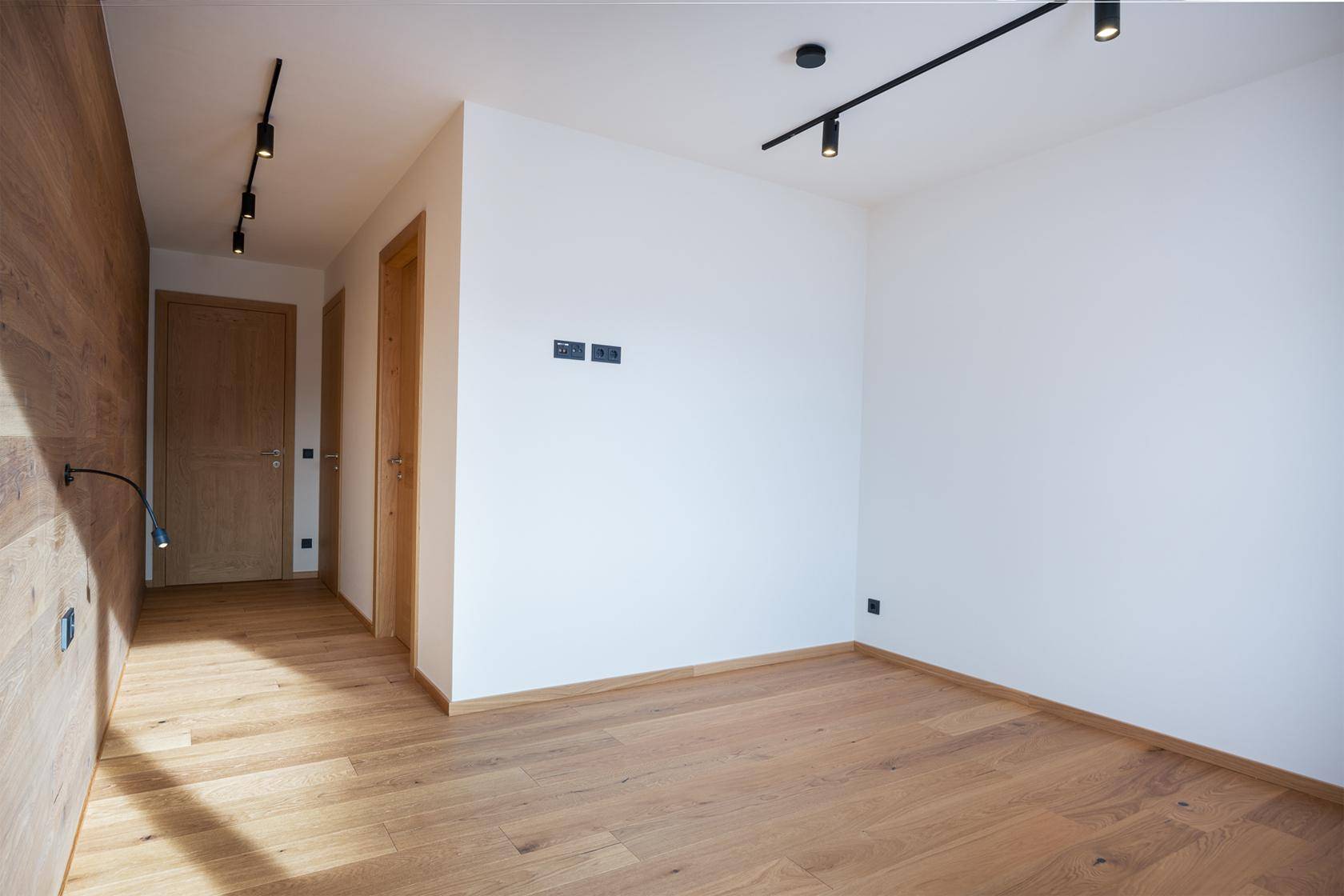 Heller Flur mit Holzboden und Holzwandverkleidung, der zu weiteren Räumen führt.