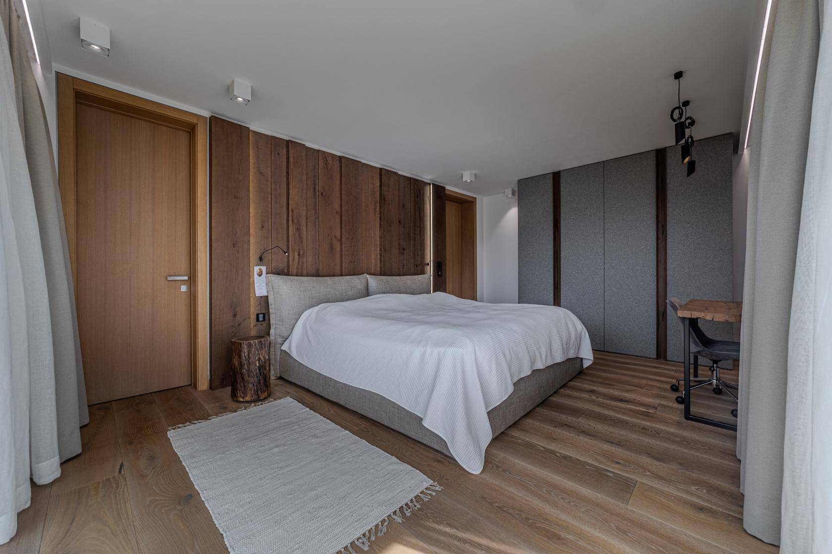 Modernes Schlafzimmer mit Holzwandverkleidung, Parkettboden und minimalistischer Einrichtung.