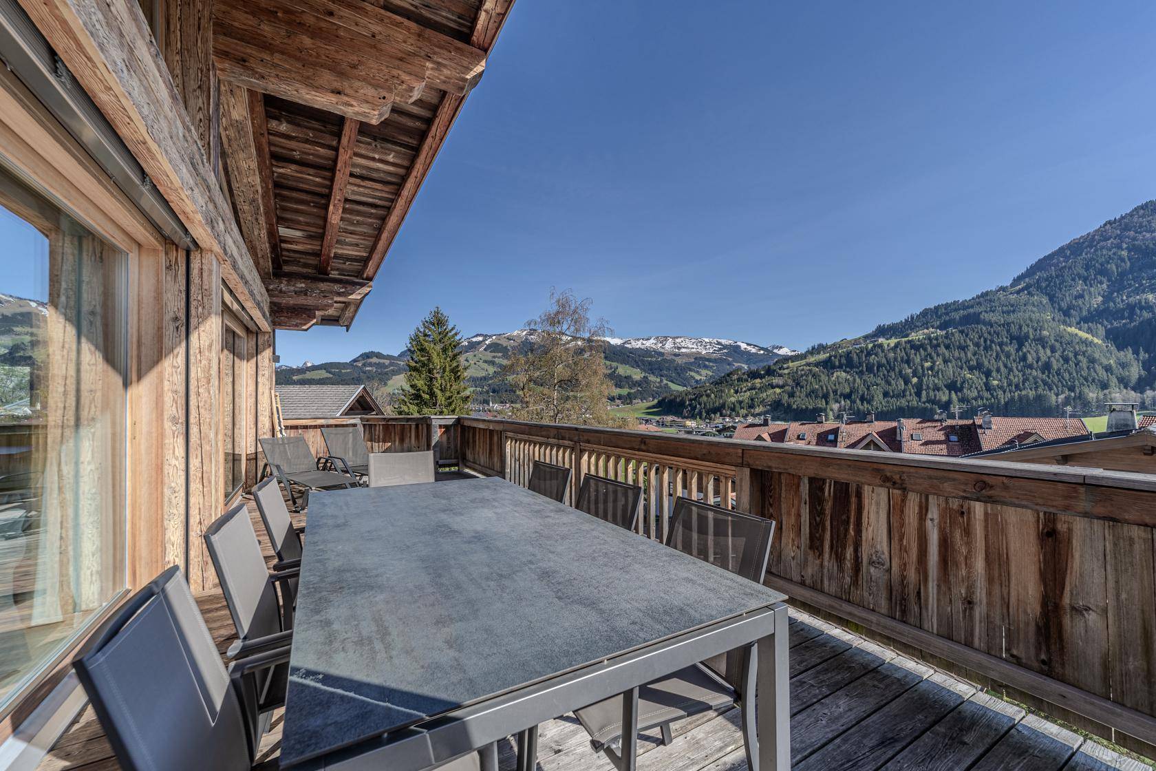 Geräumiger Balkon mit Esstisch und Stühlen, bietet einen weiten Bergblick.