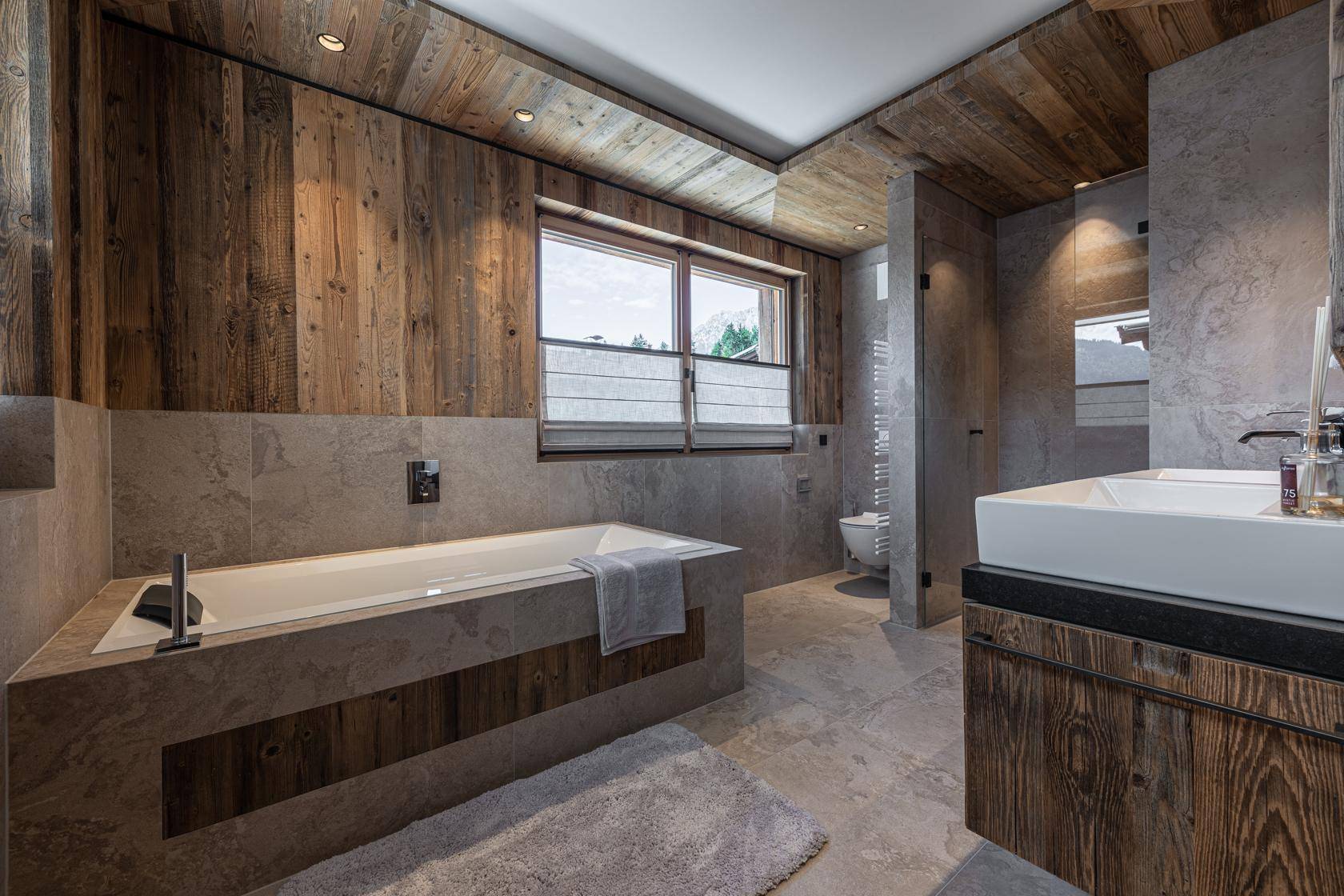 Modernes Badezimmer mit Badewanne, separater Dusche, Doppelwaschbecken und Holzelementen.