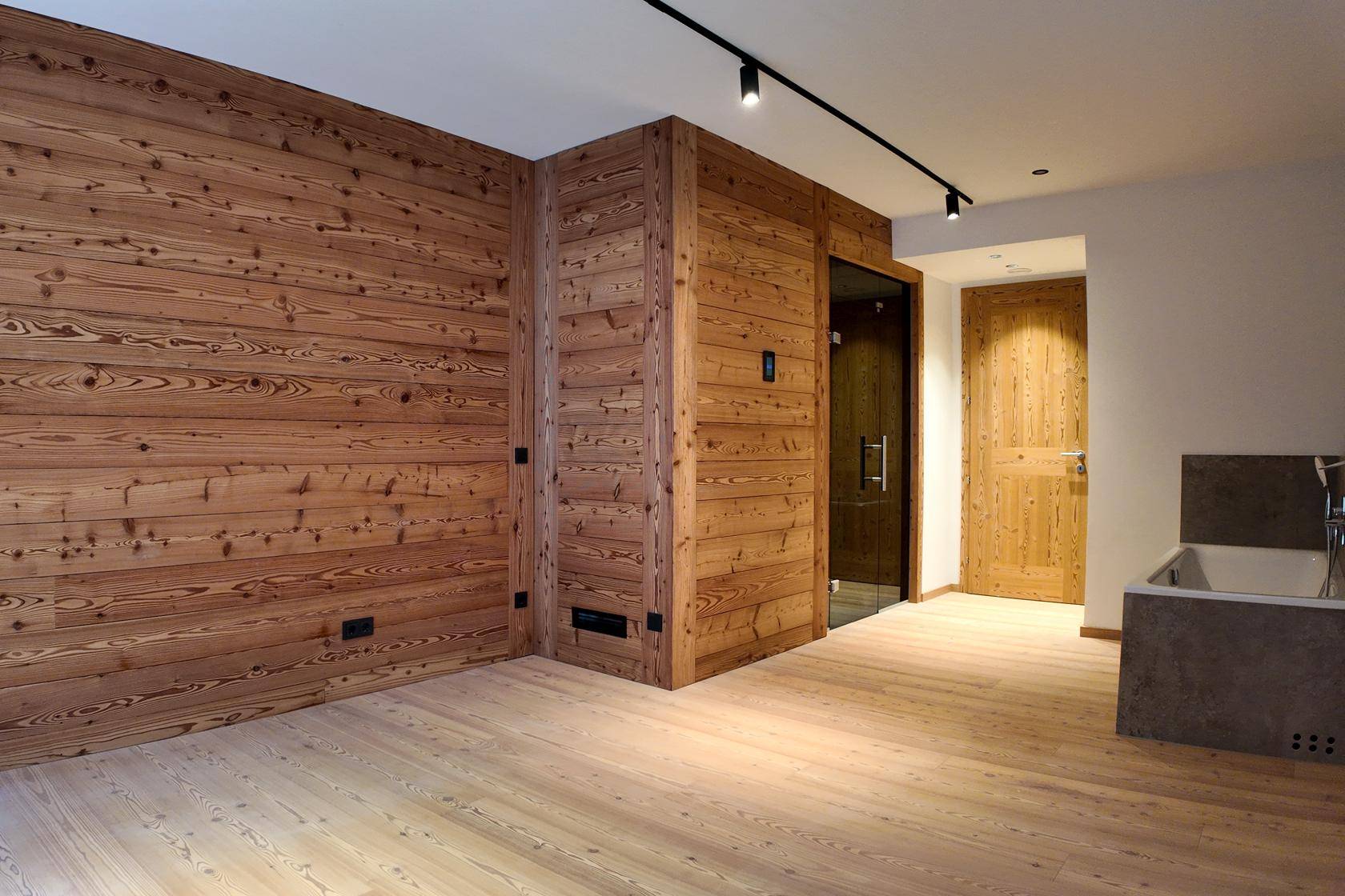 Raum mit Holzelementen, integrierter Sauna und einer modernen Badewanne, ideal zur Entspannung.