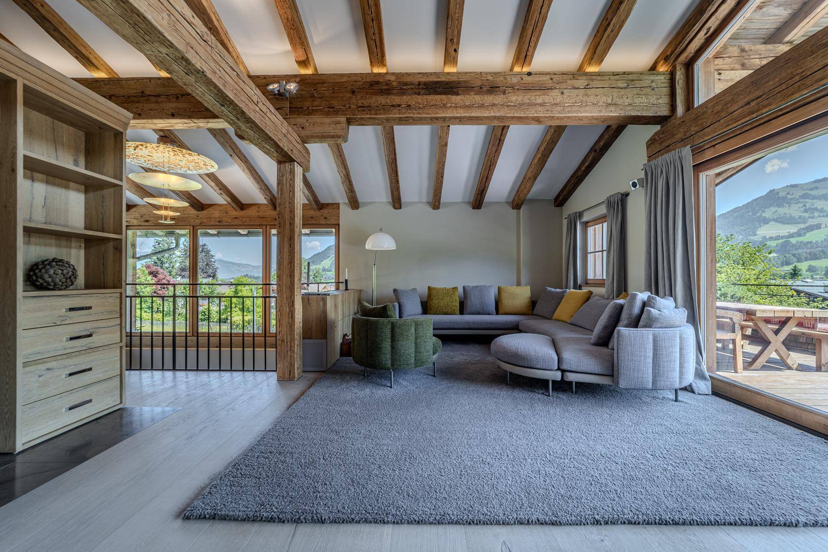 Gemütliches Wohnzimmer mit großem Sofa, Holzbalken und Zugang zur Terrasse.