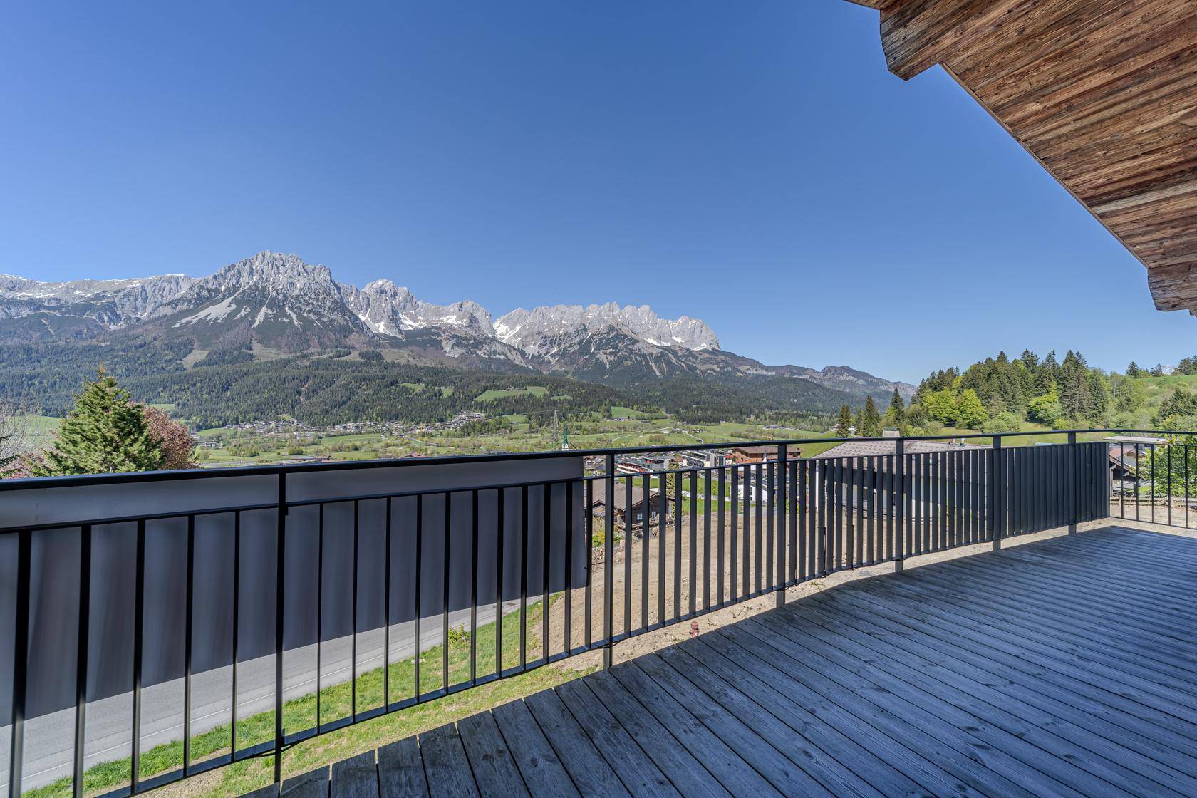 Große Holzterrasse mit Metallgeländer und weitem Blick auf die umliegende Berglandschaft.