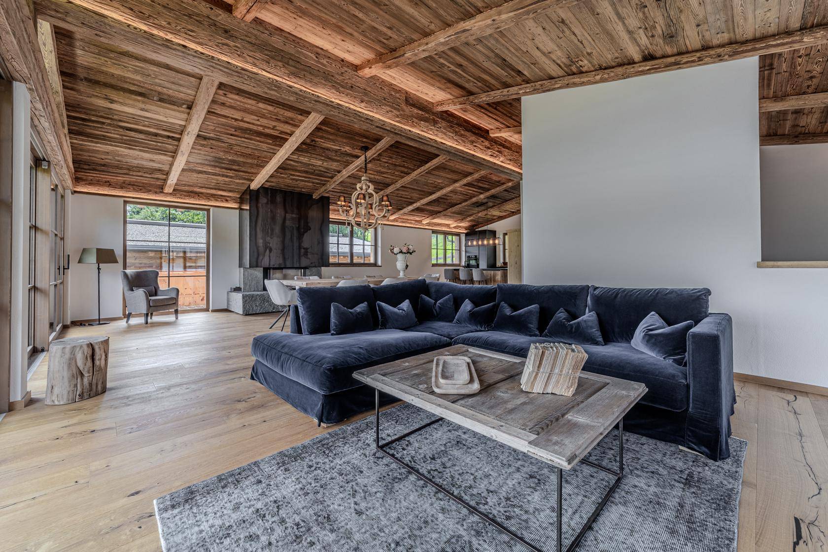 Gemütliches Wohnzimmer mit großem Sofa, Holzbalkendecke und beeindruckendem Bergblick.