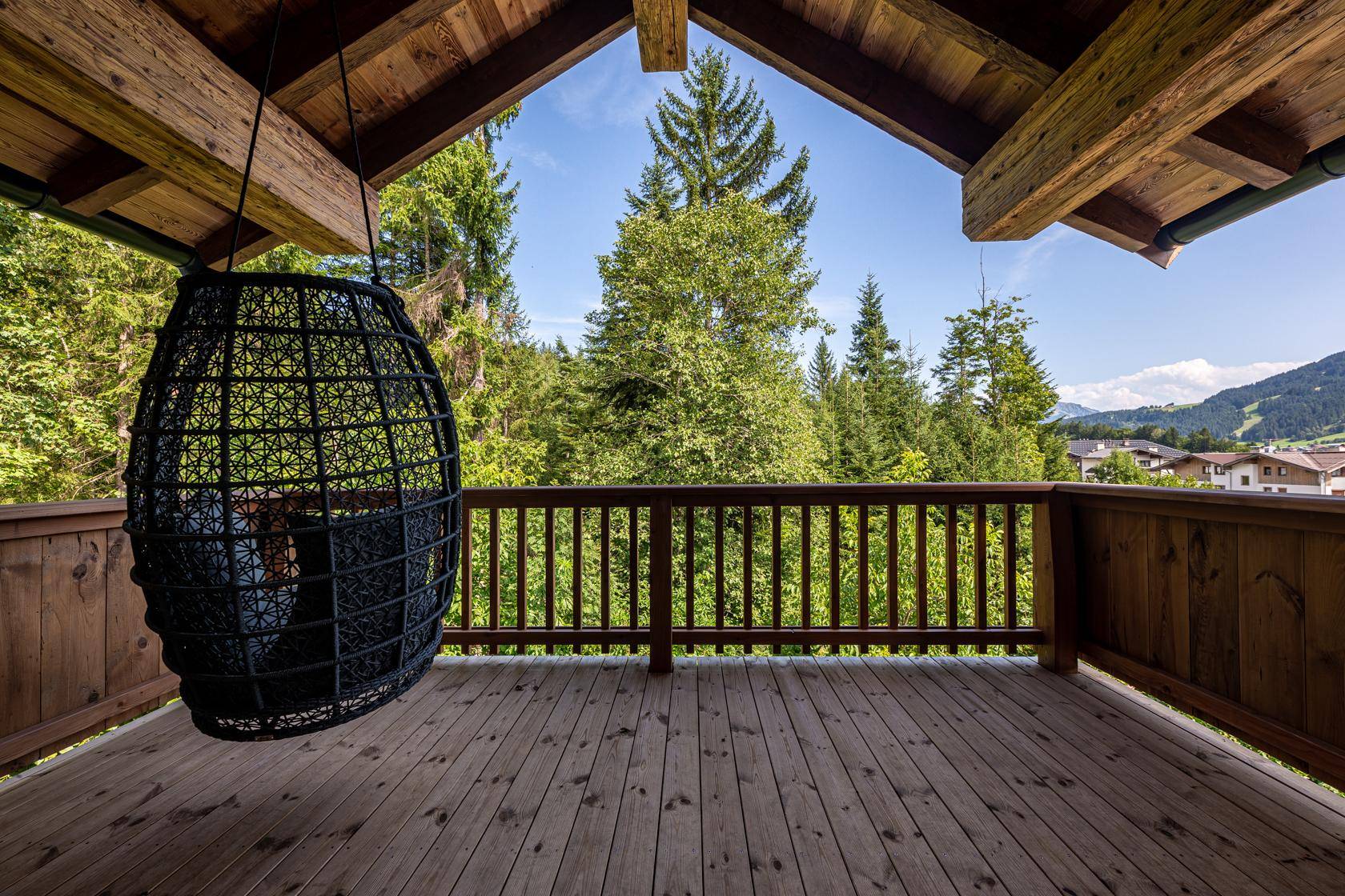 Geräumiger Holzbalkon mit Hängesessel und weitem Blick in die Natur.