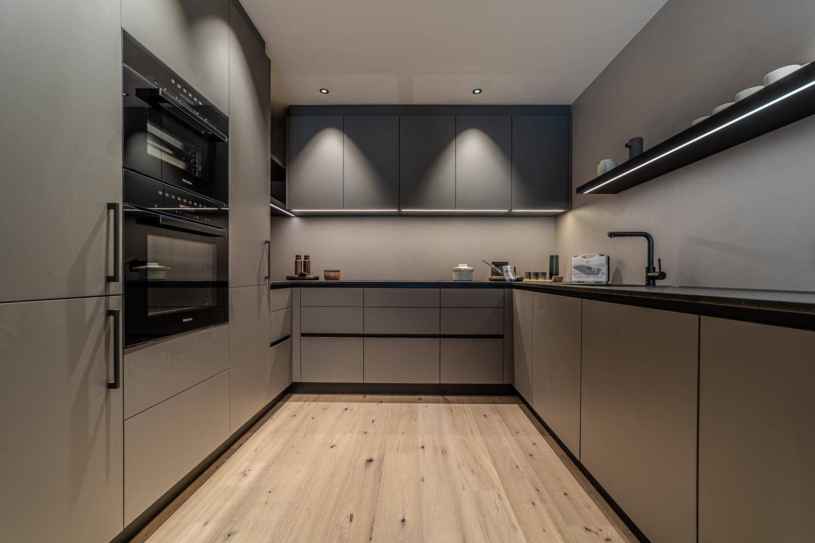 Elegante, moderne Küche mit grauen Schränken, integrierten Geräten und hellem Holzboden.