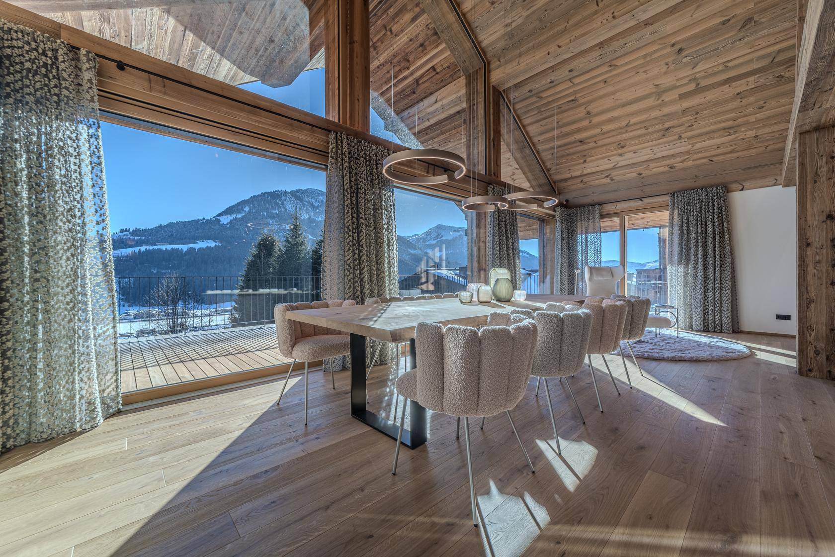 Heller Essbereich mit großen Fenstern, Holzbalken und Panoramablick auf die Berge.