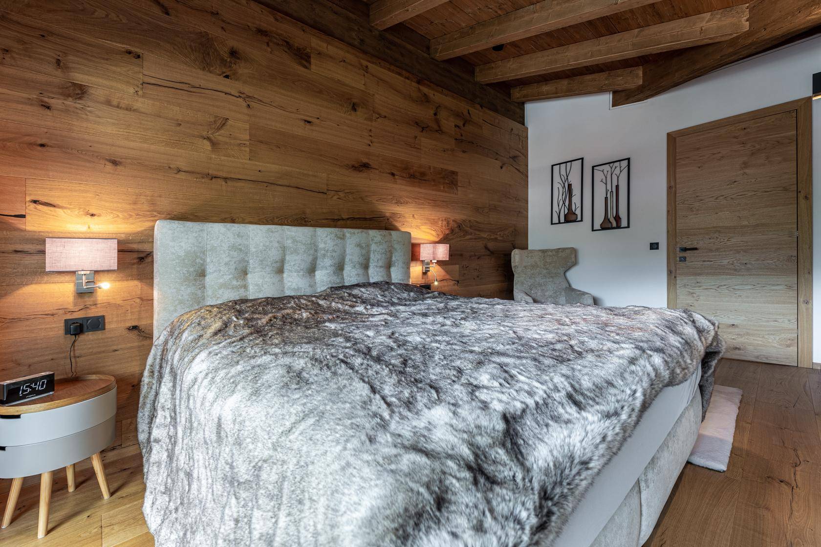 Modernes Schlafzimmer mit Holzwandverkleidung, bequemen Bett und stilvoller Beleuchtung.